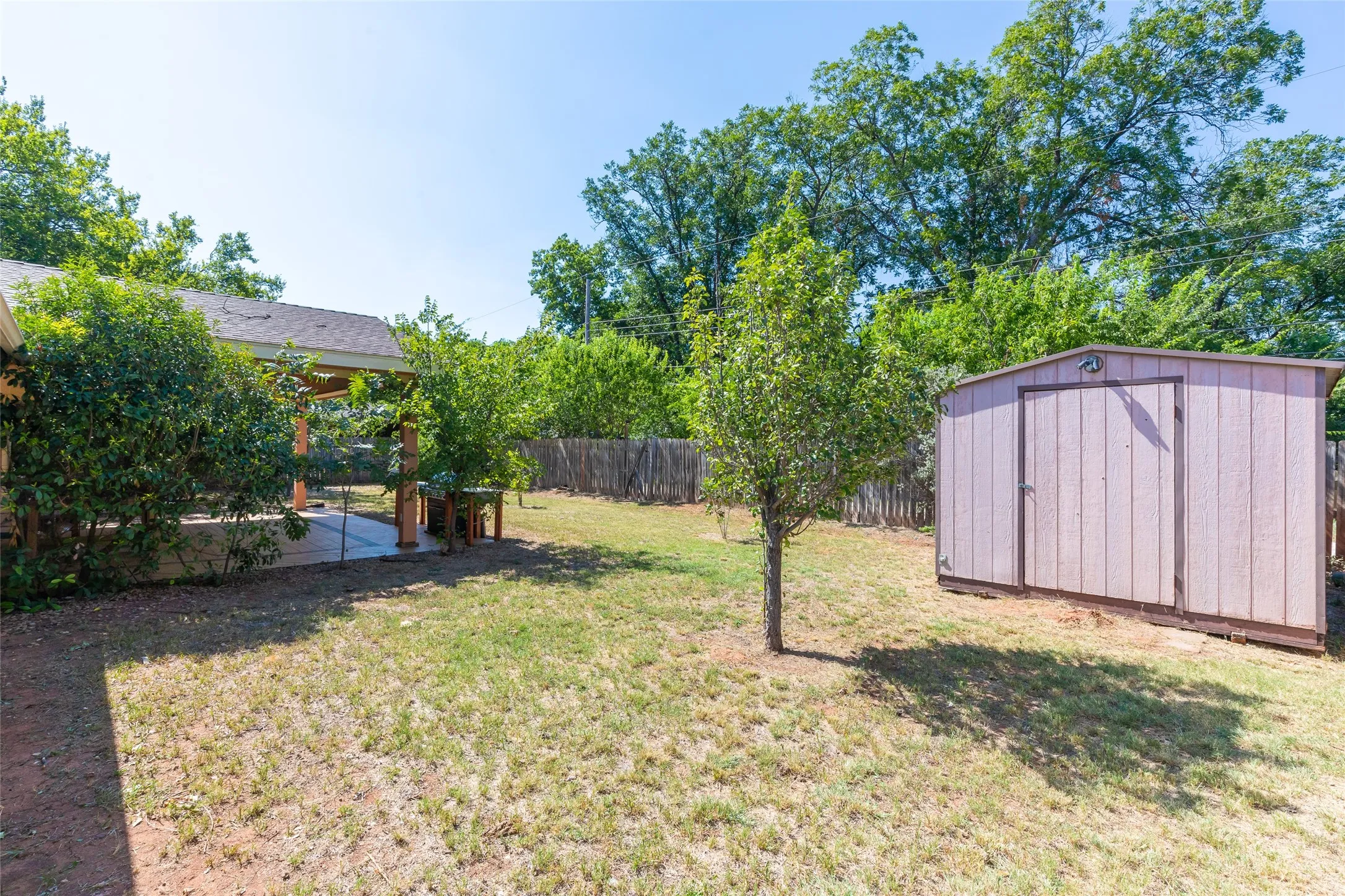 Expansive backyard featuring a storage shed, a covered patio, and mature trees