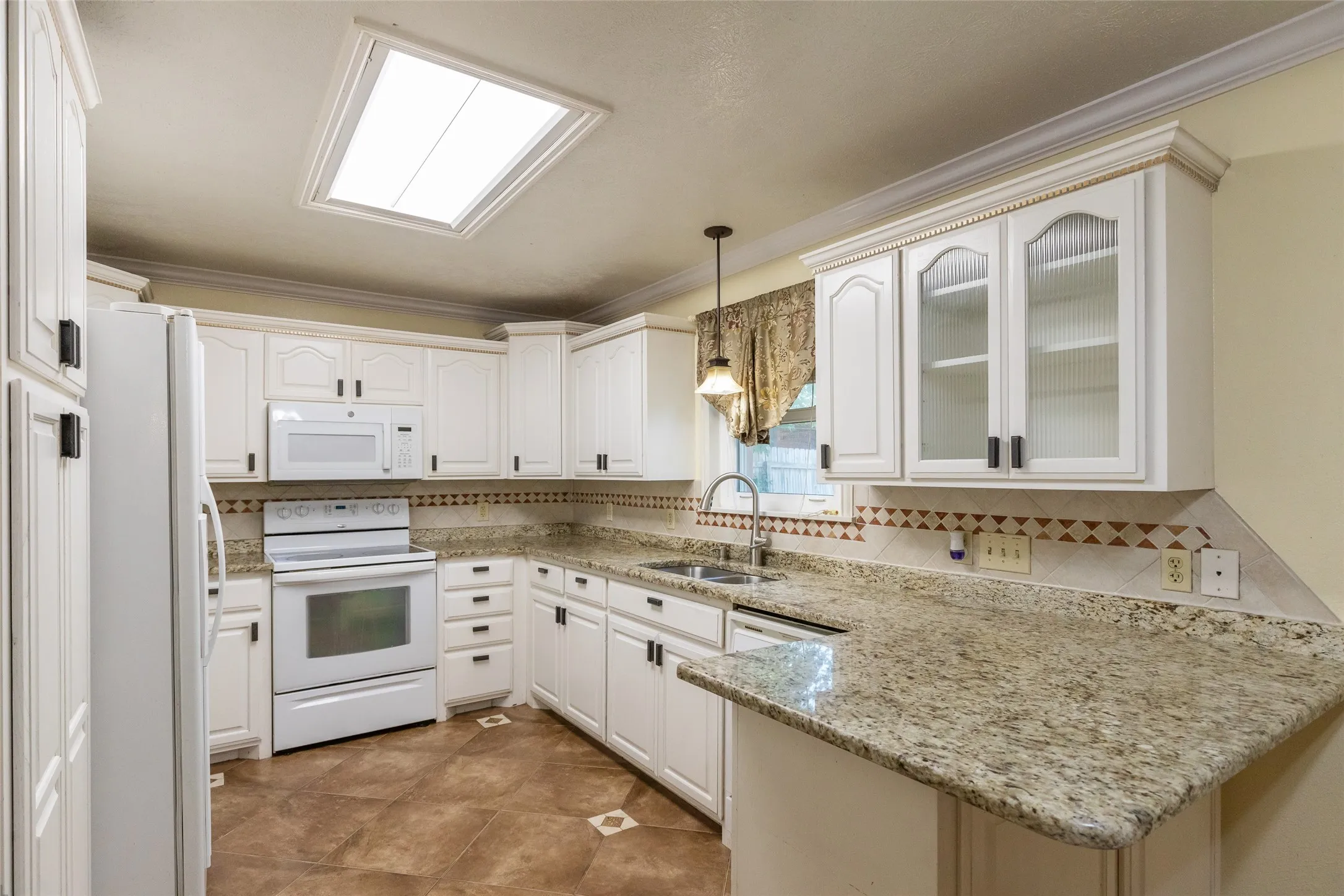 Kitchen featuring white cabinetry with dark hardware, stone countertops, and a tiled backsplash