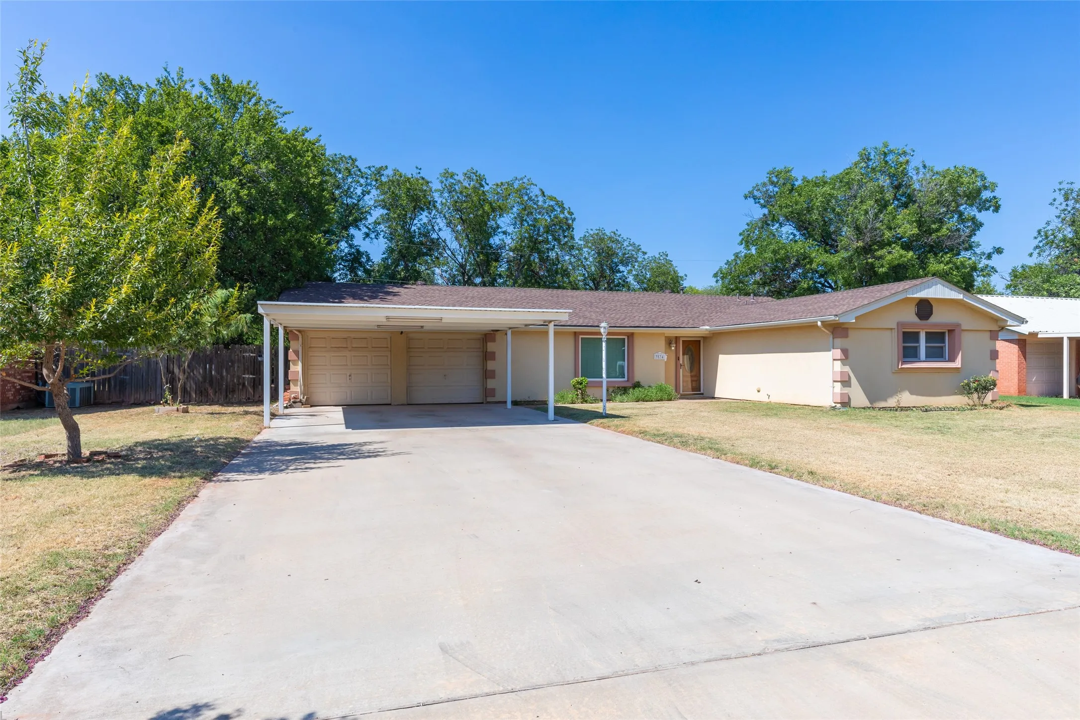 Single-story residence featuring a two-car garage with overhead doors, a covered carport, and a concrete driveway