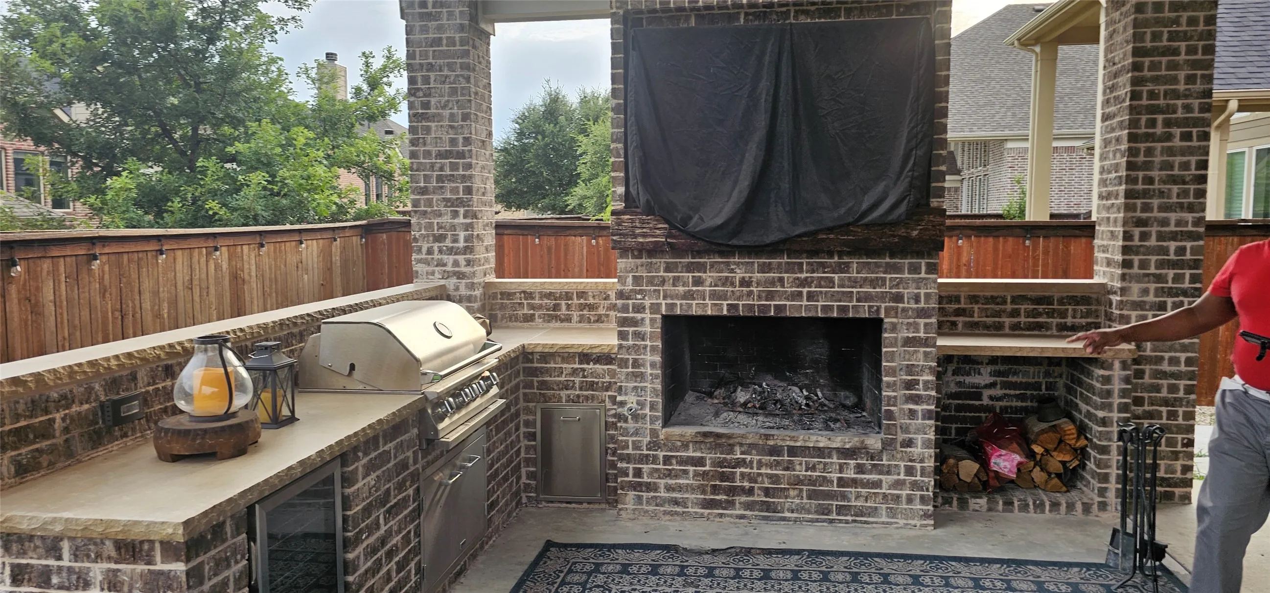 Outdoor living area featuring a built-in brick fireplace, integrated grill, and extensive counter space