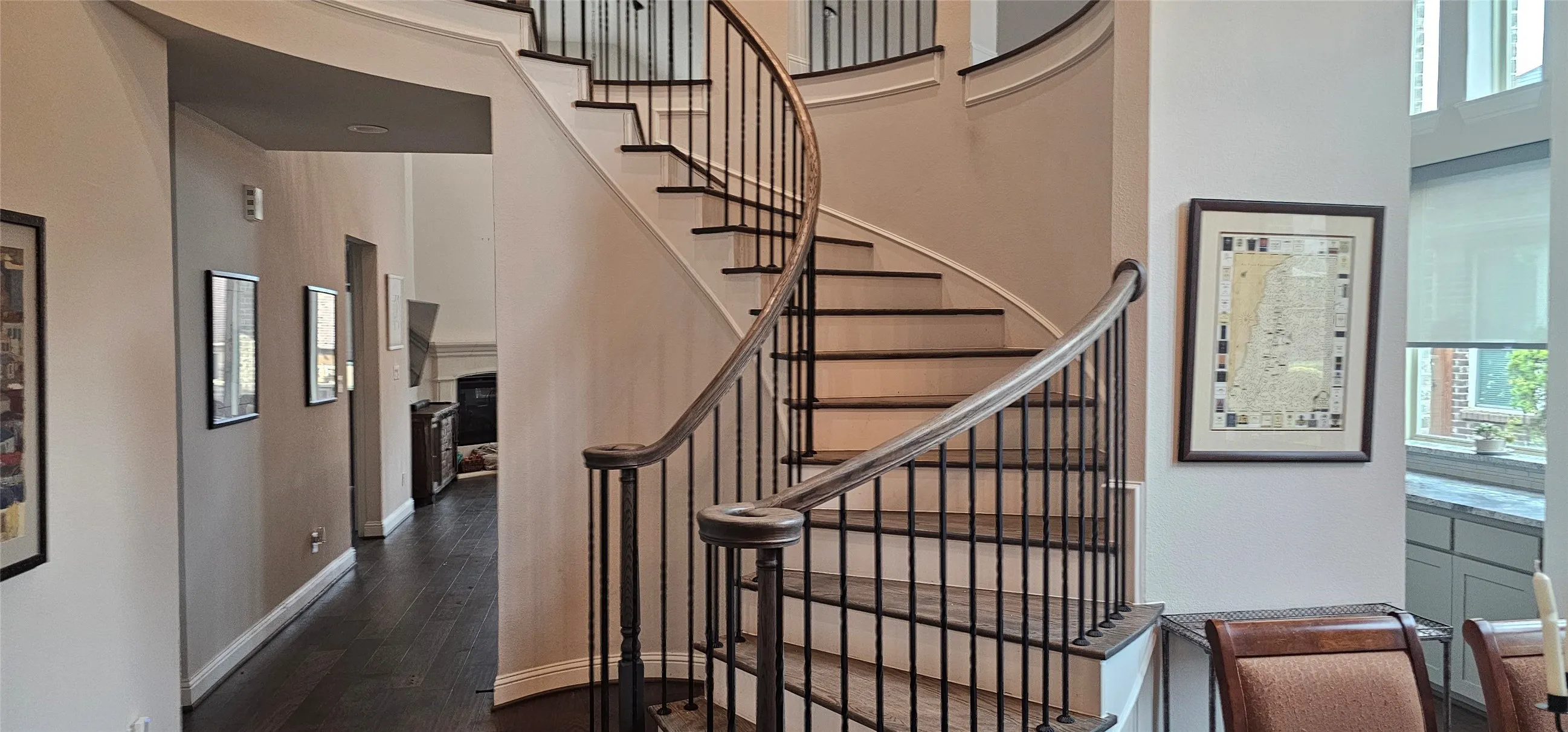 Curved staircase featuring dark wood-finish handrails and black iron balusters, dark wood-finish flooring, and high ceilings