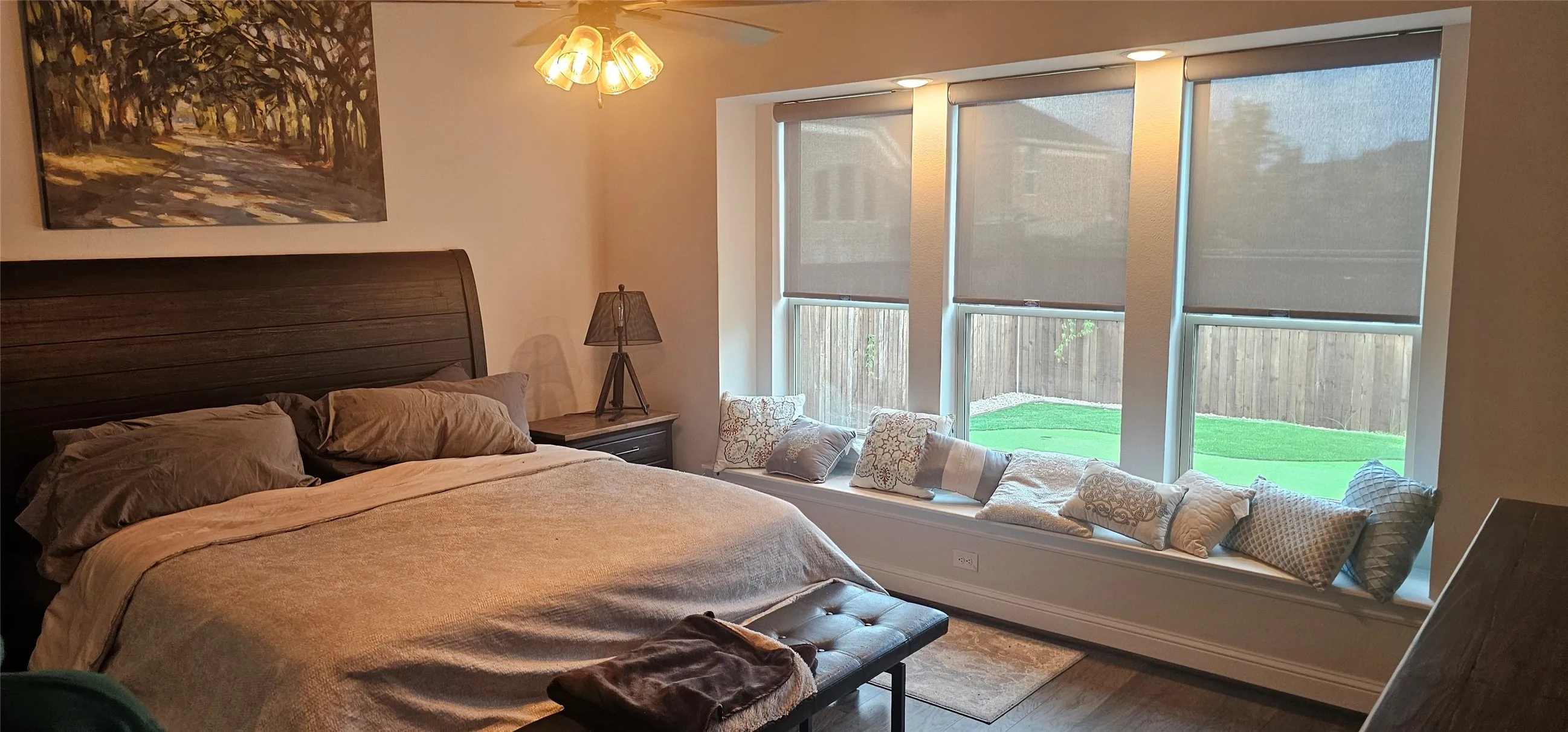 Wood-finish flooring, ceiling fan with integrated lighting, built-in window seating, multiple windows with roller shades, and recessed lighting
