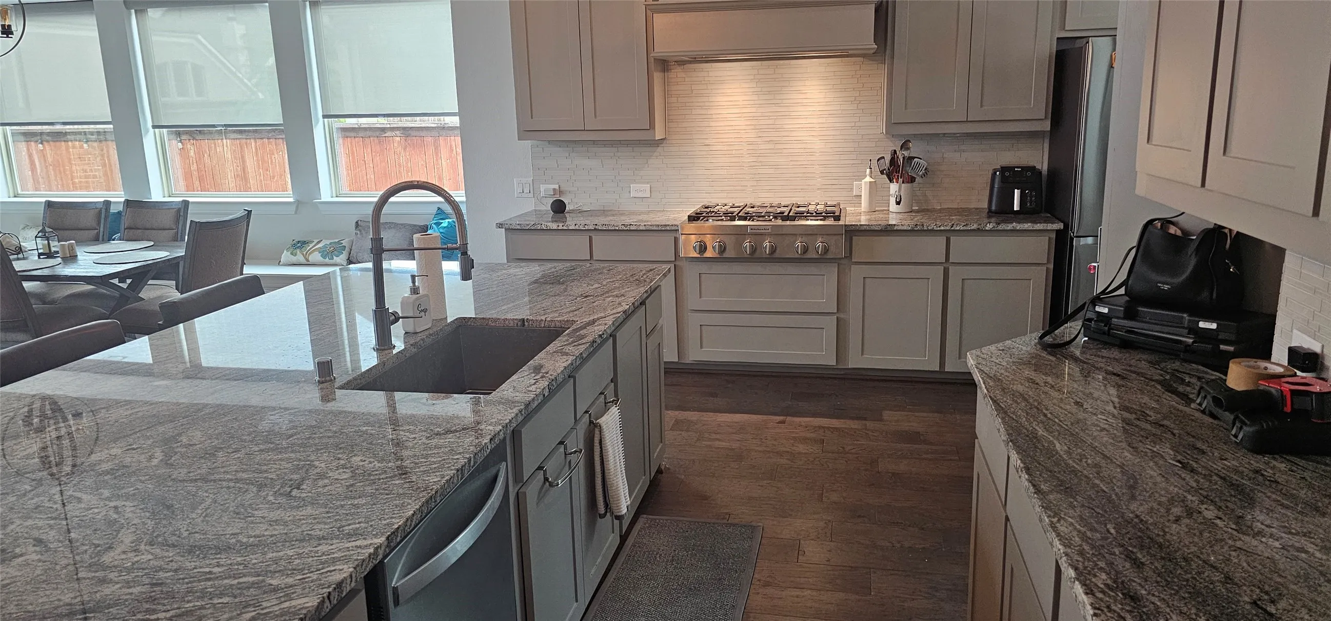 Kitchen featuring a large island with an undermount sink, stainless steel dishwasher, ample cabinet storage, and a gas range