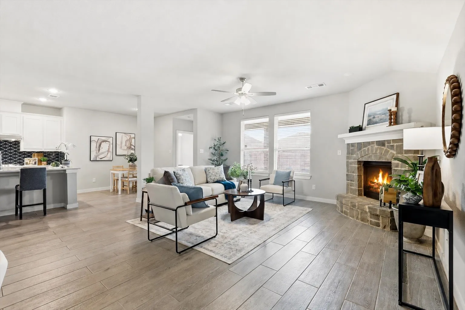 WOW! The natural lighting in this room is breathtaking. An open concept living area featuring wood look plank tile, gas fireplace with brick/stone surrounding, flat screen wiring with two dining spaces, or additional sitting etc with views of the kitchen