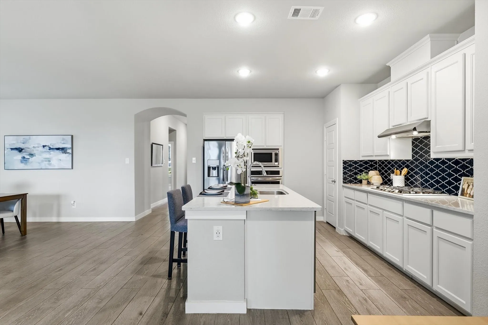 Open-concept kitchen with stylish backsplash, ss appliances. gas cooktop, large island, plenty of storage and bright lighting!