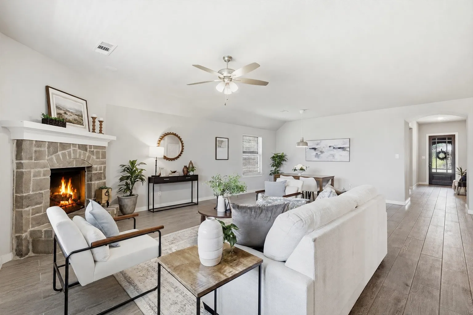 WOW! The natural lighting in this room is breathtaking. An open concept living area featuring wood look plank tile, gas fireplace with brick/stone surrounding, flat screen wiring with two dining spaces, or additional sitting etc with views of the kitchen