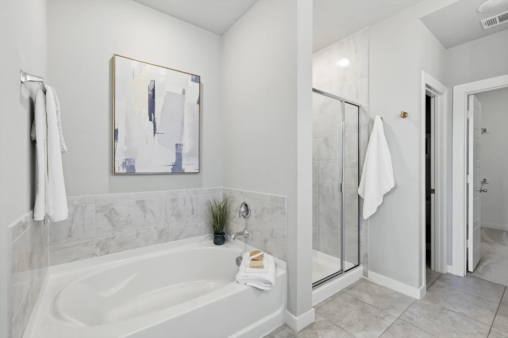 Large primary bathroom with dual vanities, make up or sitting space, separate shower and soaking tub with massive walk in closet.