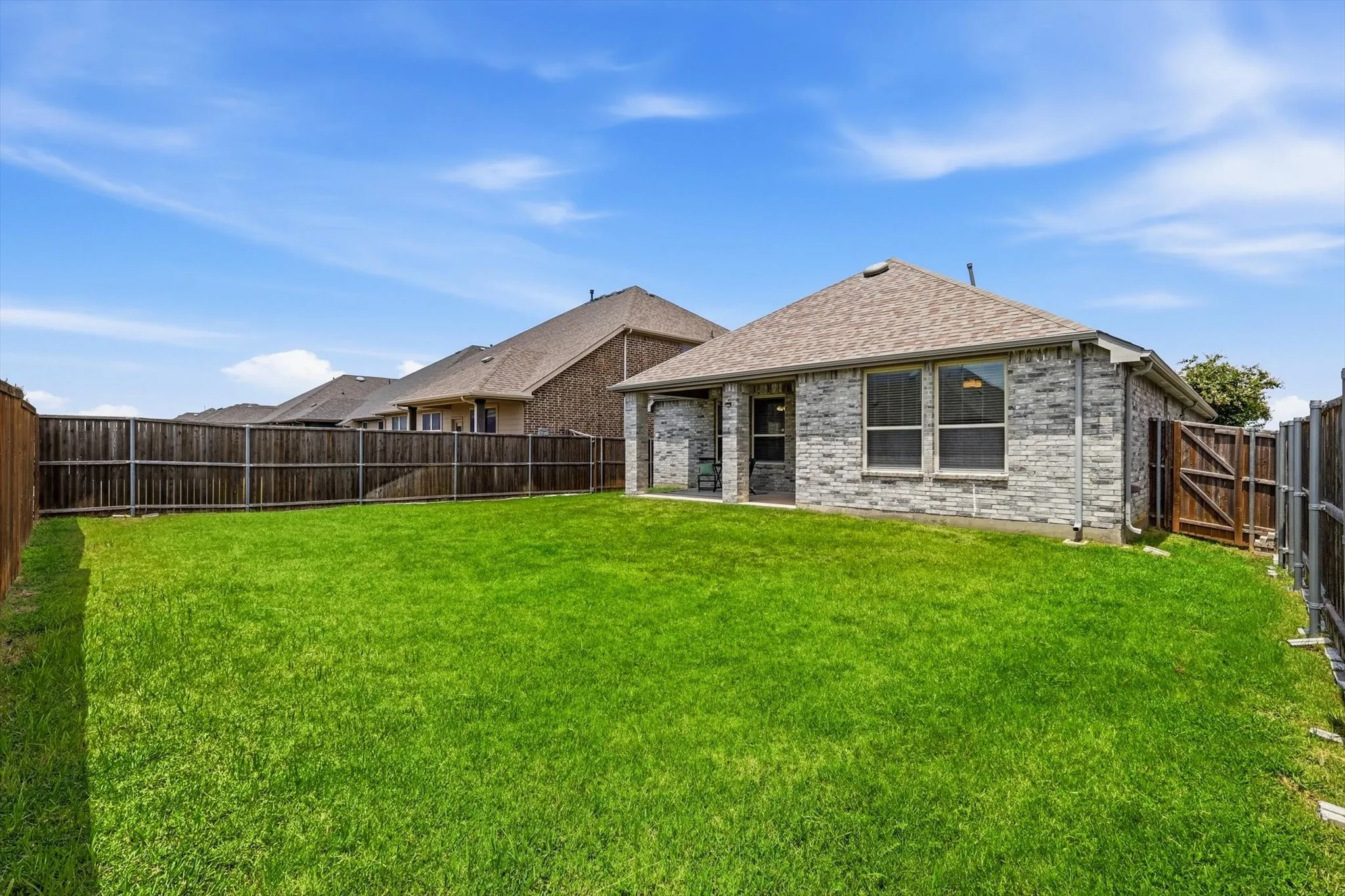 Expansive backyard featuring a lush green lawn and full privacy fencing