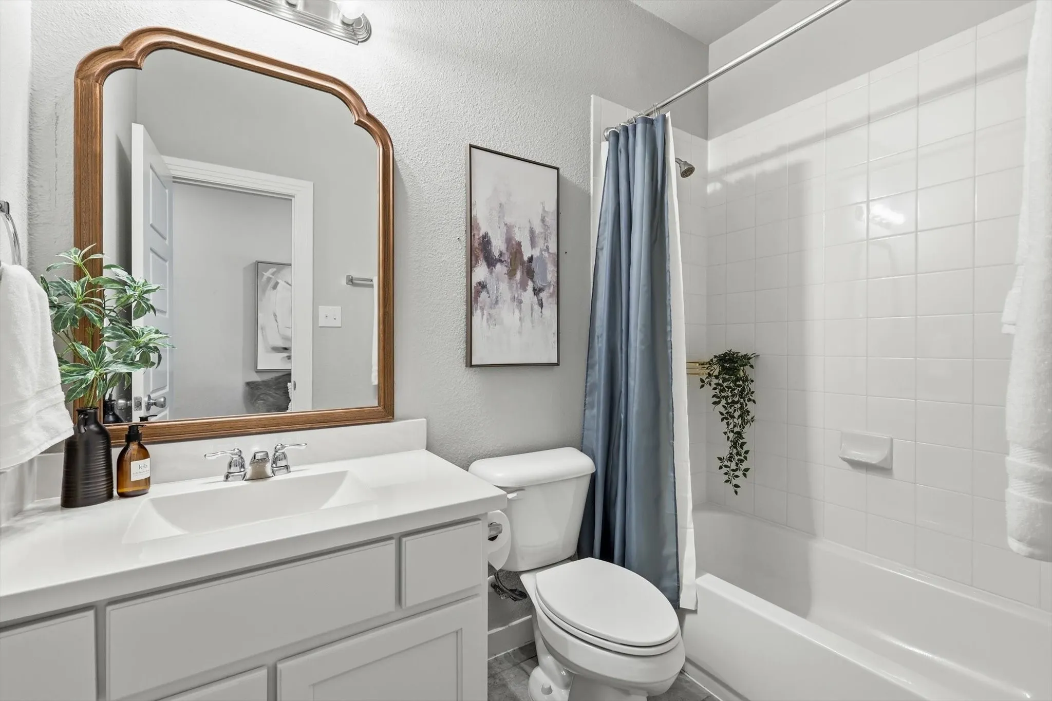 Bright and functional secondary bathroom featuring a white vanity with a custom wood framed mirror and built in cabinetry.