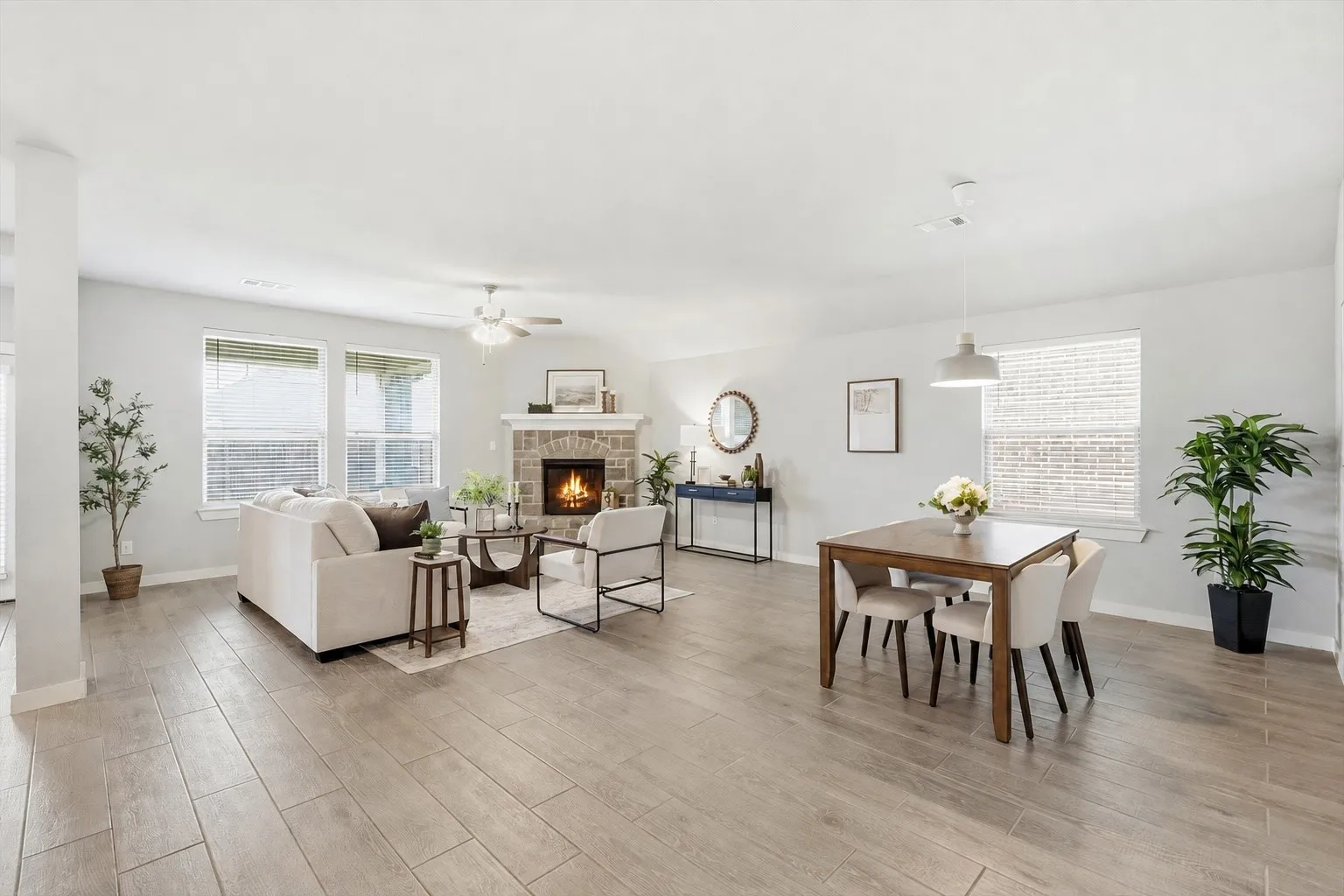 WOW! The natural lighting in this room is breathtaking. An open concept living area featuring wood look plank tile, gas fireplace with brick/stone surrounding, flat screen wiring with two dining spaces, or additional sitting etc with views of the kitchen