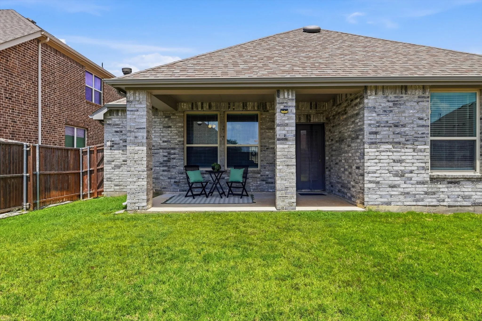 Covered rear patio featuring a concrete slab and gray brick facade