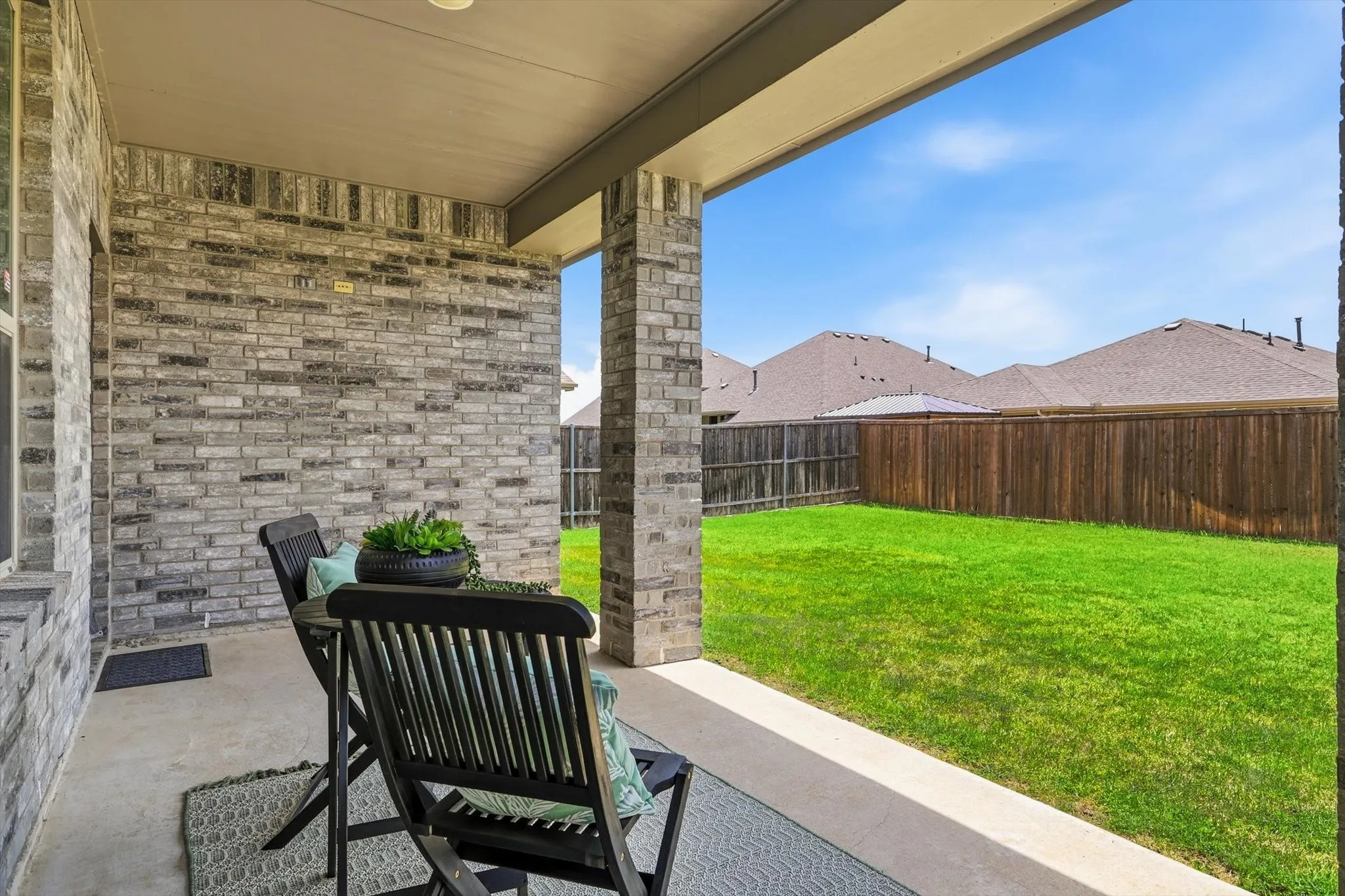 Covered rear patio featuring a concrete slab and gray brick facade