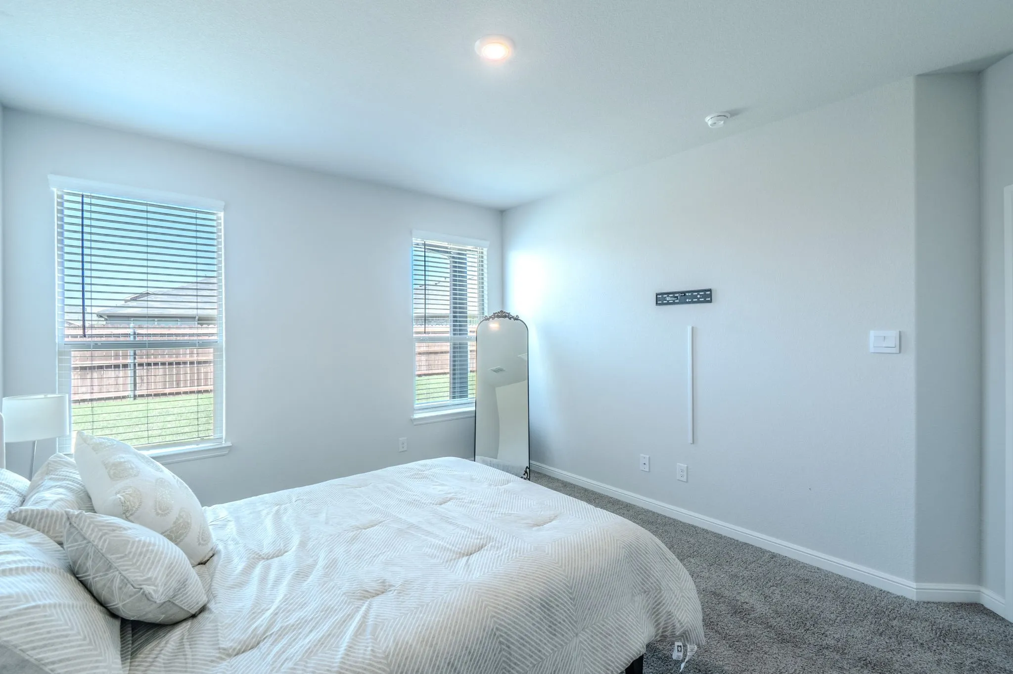 Carpeted interior space featuring light gray walls, two windows with blinds, and a built-in ceiling light