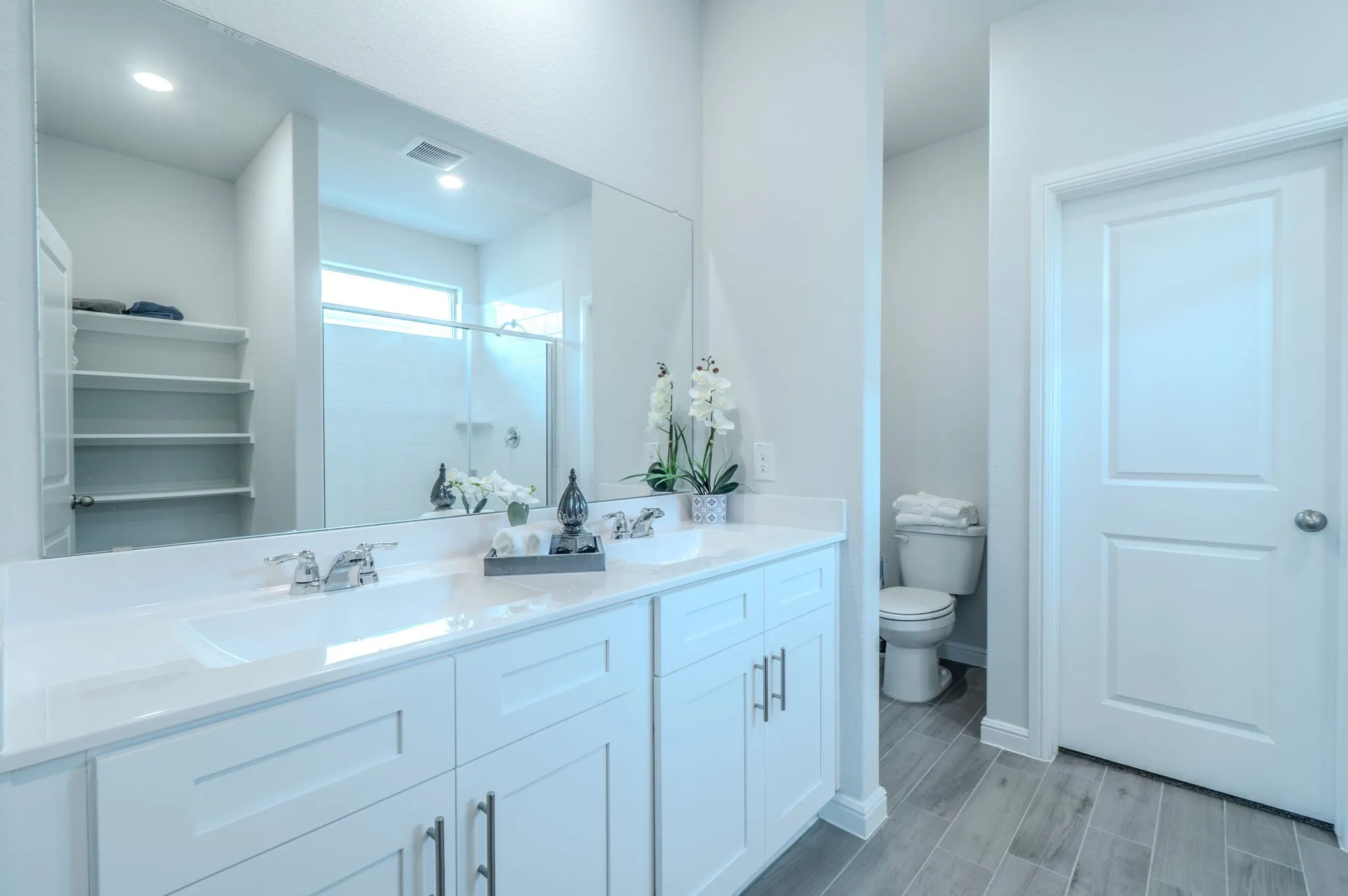 Dual white vanity with undermount sinks, chrome fixtures, and a large wall-mounted mirror