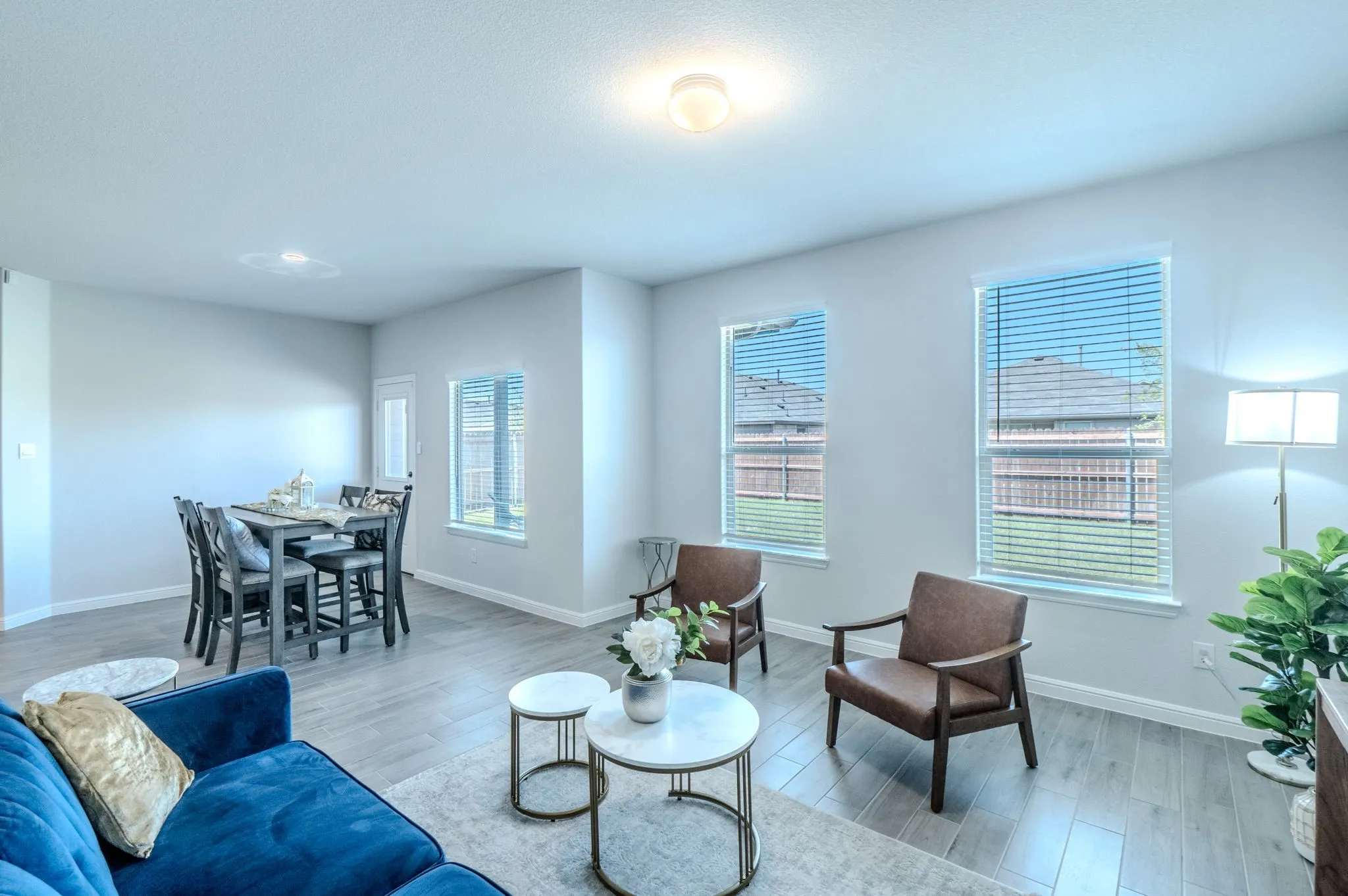 Open-concept living space featuring wood-finish flooring, recessed lighting, and multiple windows with blinds