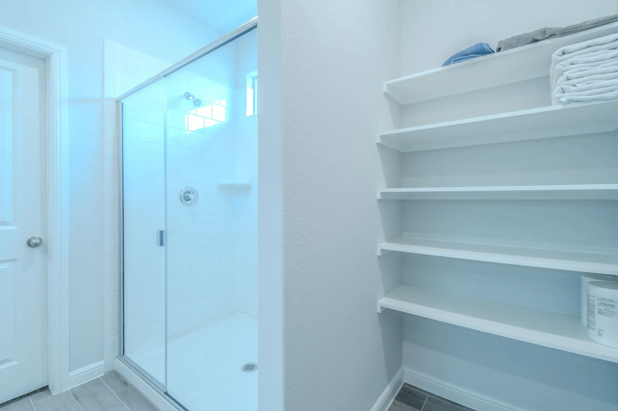 Walk-in shower with clear glass enclosure and subway tile surround, complemented by a built-in shelving unit