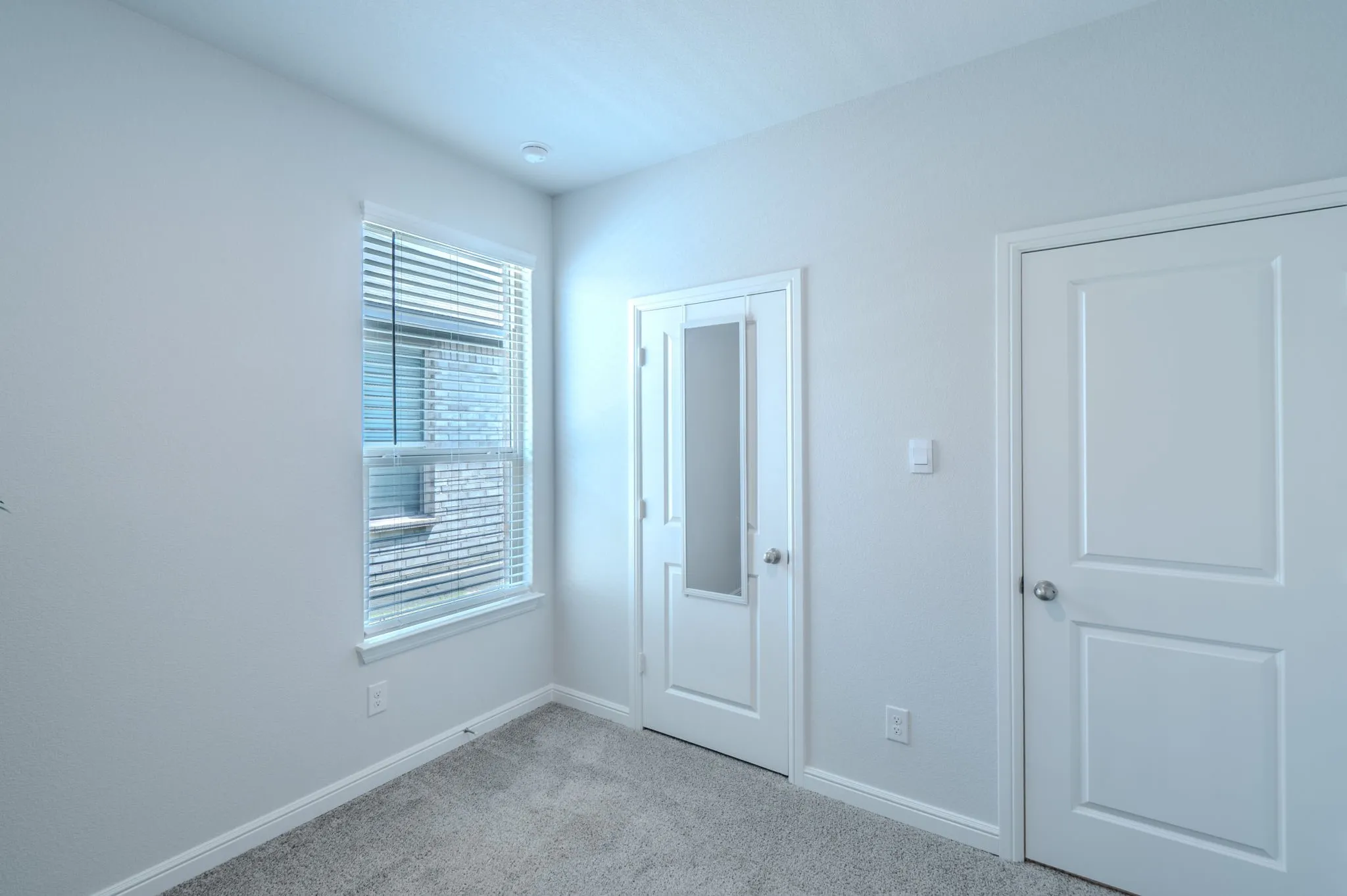 Carpeted room with a double-pane window featuring horizontal blinds