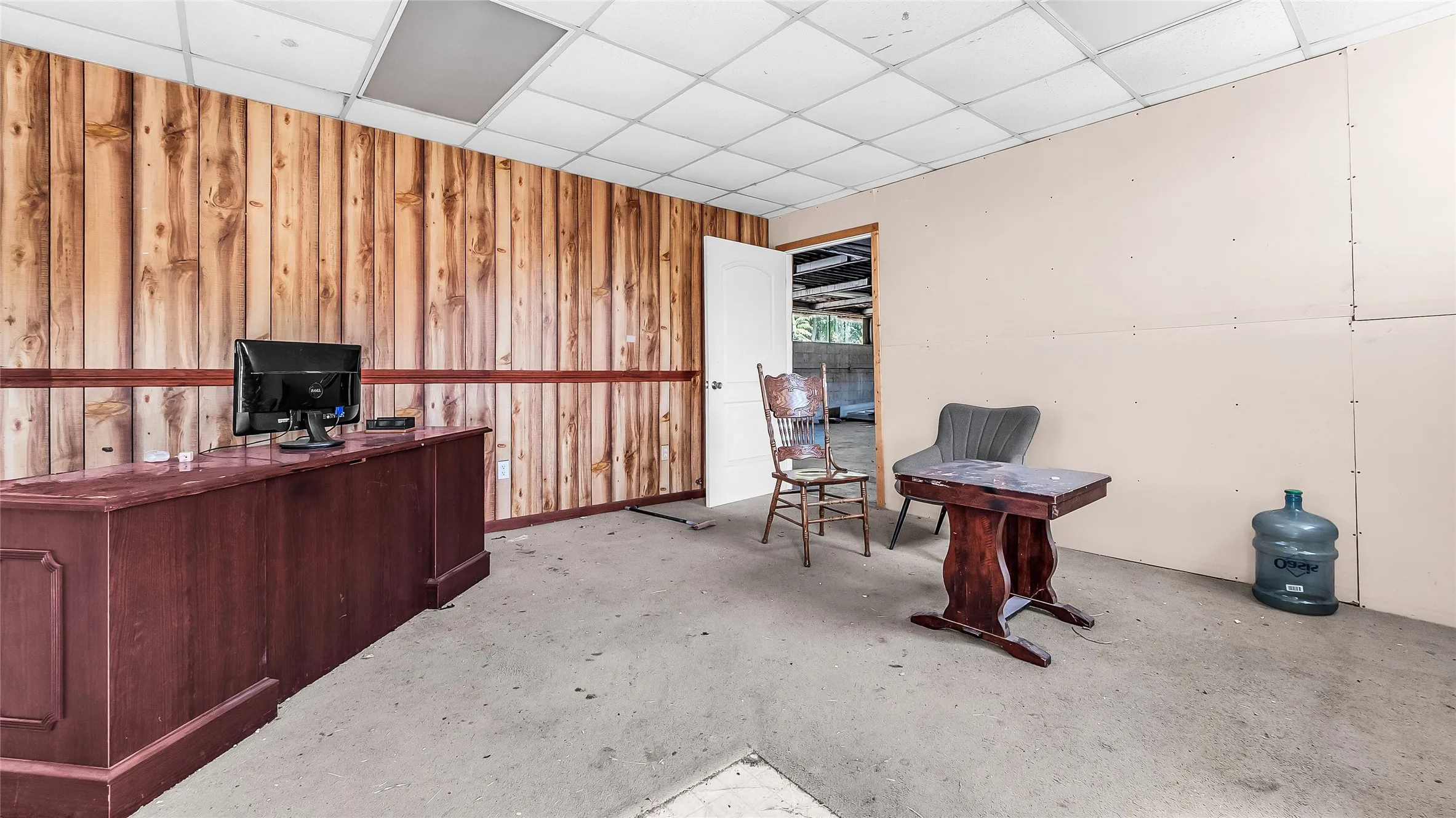 Wood-paneled wall, drop ceiling, and an interior door frame