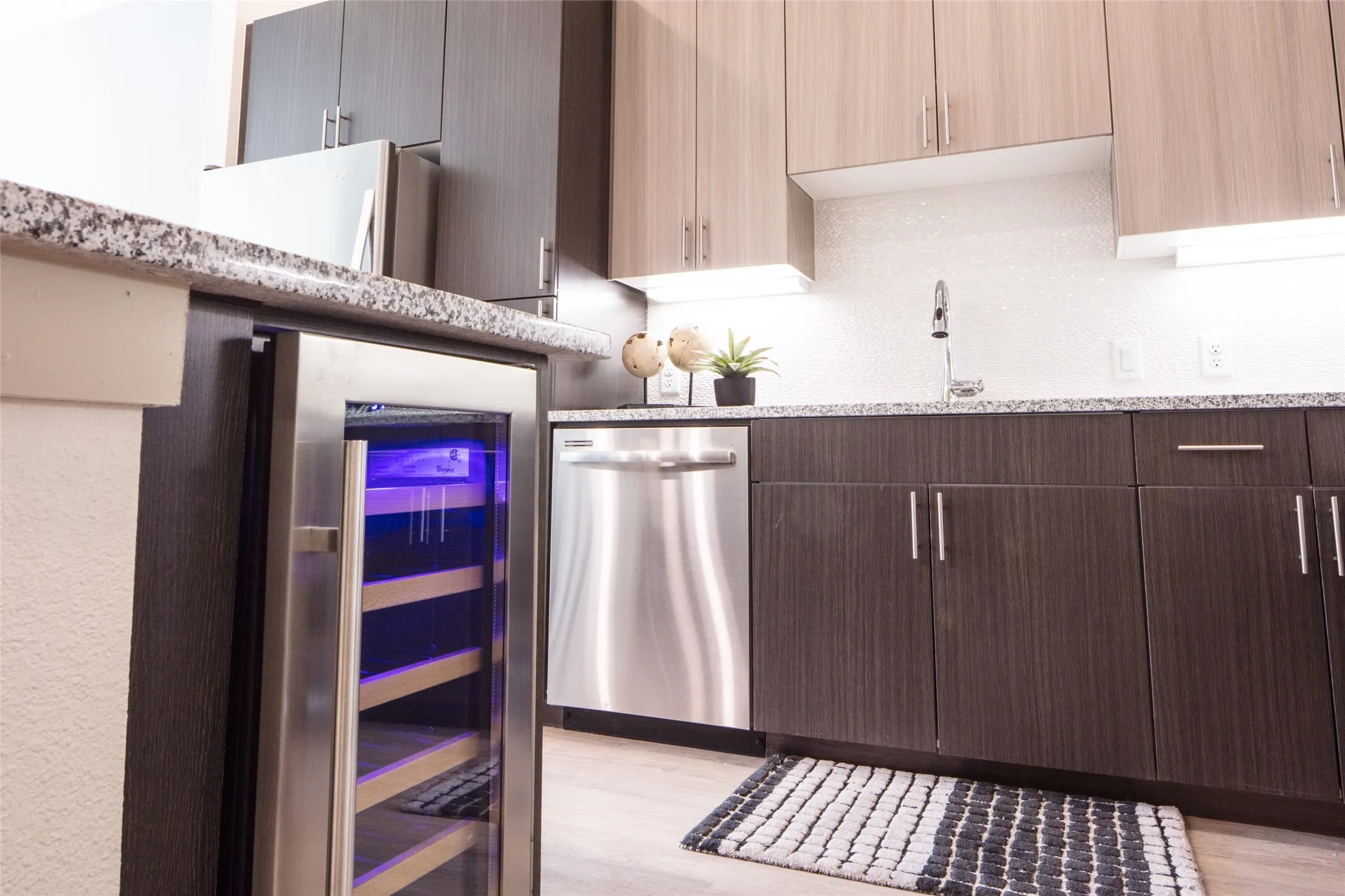 Kitchen featuring wine cooler, light stone countertops, light hardwood / wood-style flooring, stainless steel dishwasher, and sink