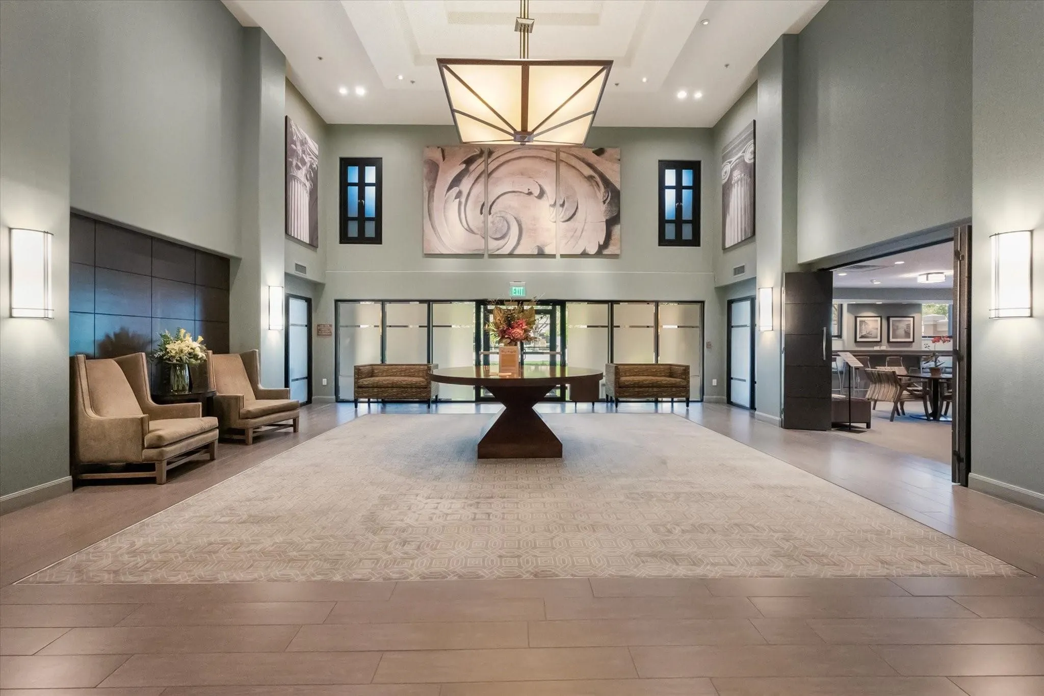Spacious lobby featuring wood-finish flooring, a large area rug, and high ceilings
