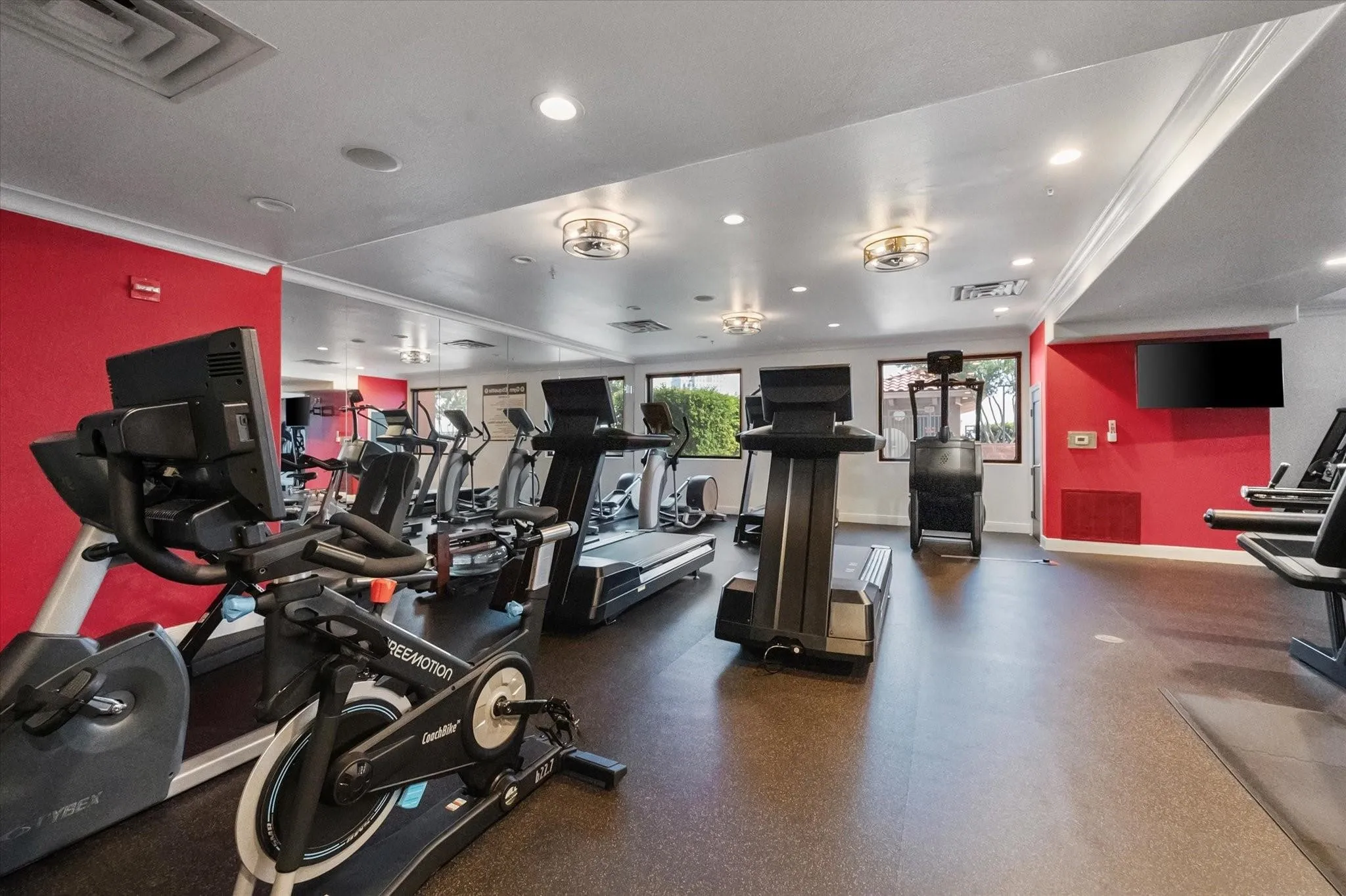 Fitness room featuring a variety of exercise equipment, rubberized flooring, mirrored walls, recessed lighting, and crown molding