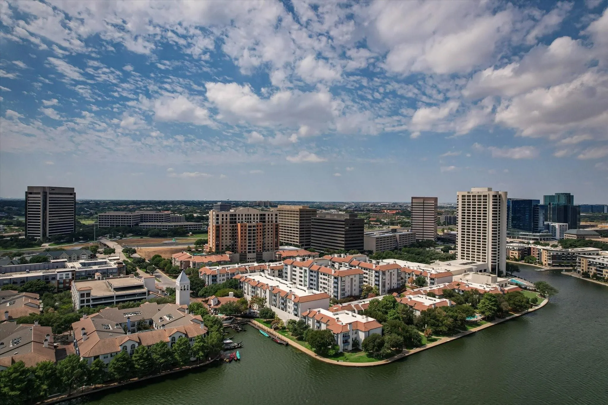 Waterfront residential properties with tiled roofs and surrounding green spaces