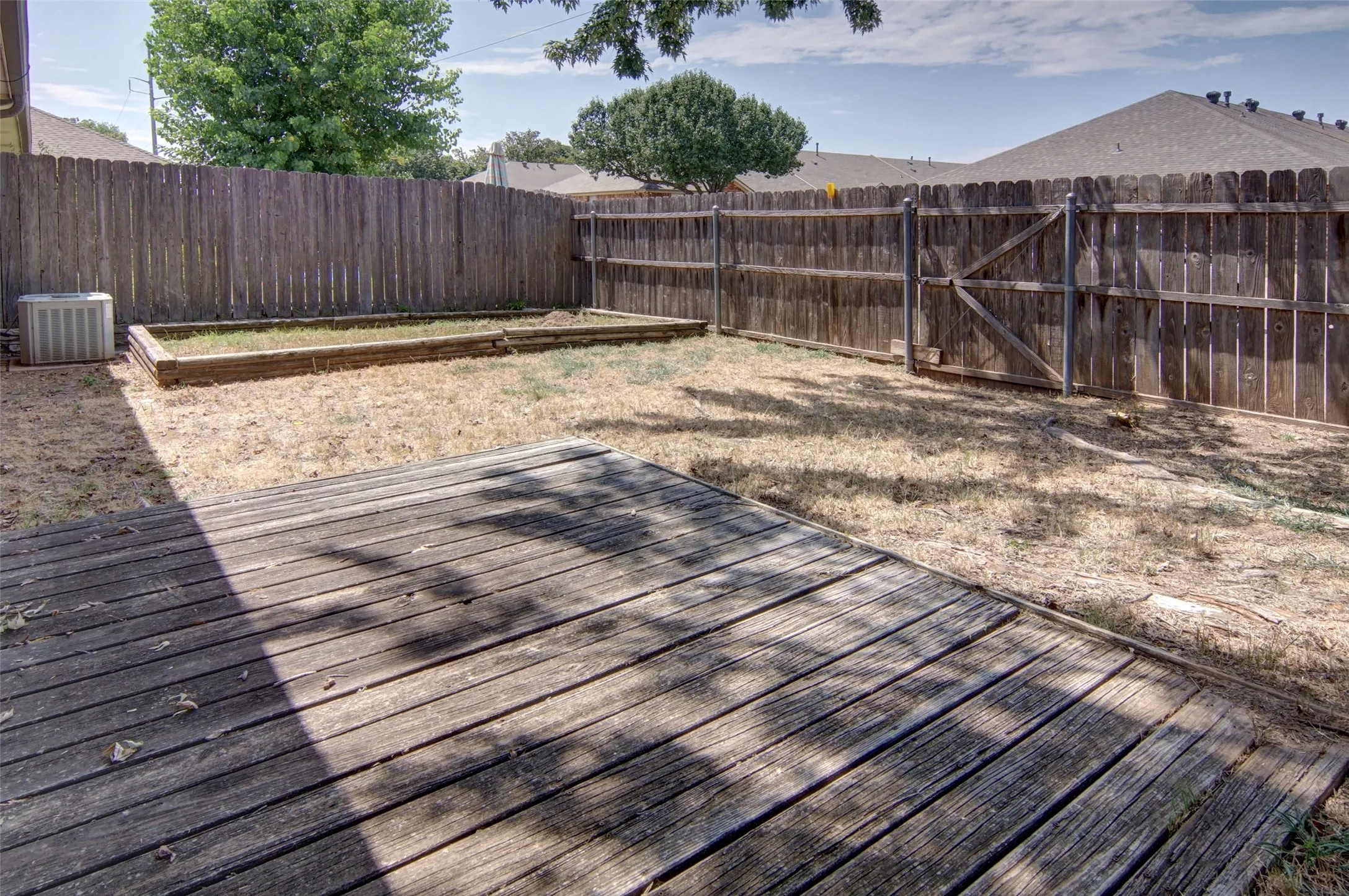 fully fenced backyard with a wooden deck