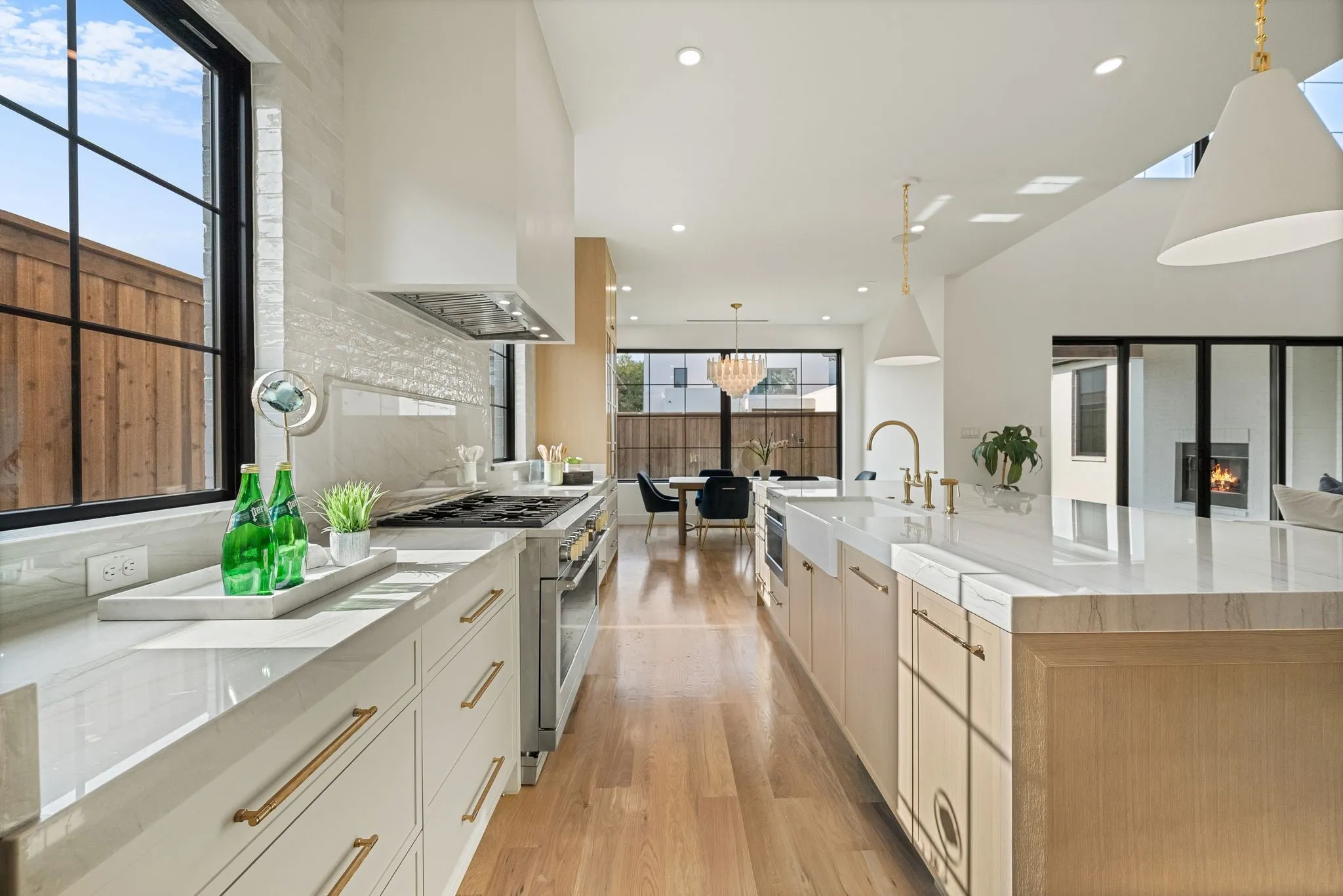 Gourmet kitchen with extensive white countertops, a large center island with a farmhouse sink, stainless steel appliances, and wood-finish flooring