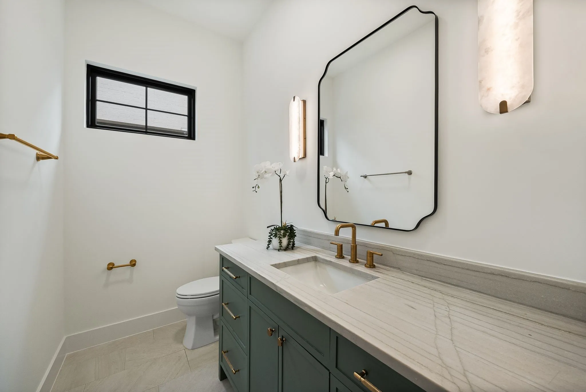 Bathroom featuring a green vanity with brass hardware, a white undermount sink, and a light-toned countertop