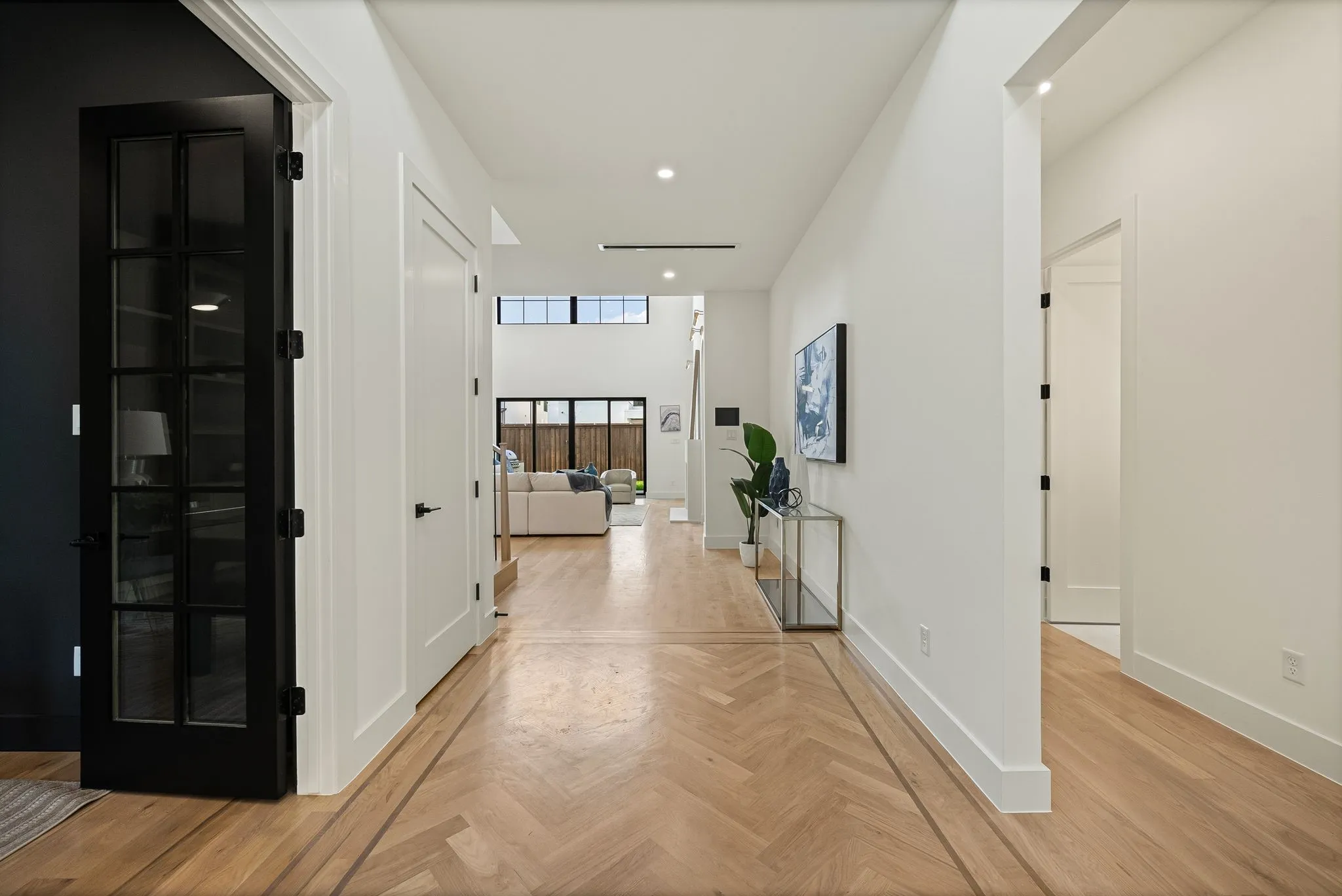 Herringbone wood-finish flooring with a perimeter inlay, white walls, and recessed lighting
