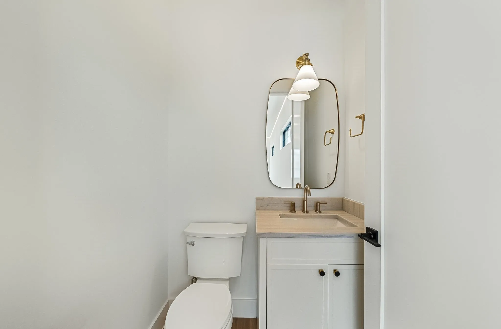 Powder room featuring a white single vanity with light-toned countertop, an integrated sink, and gold-finish hardware