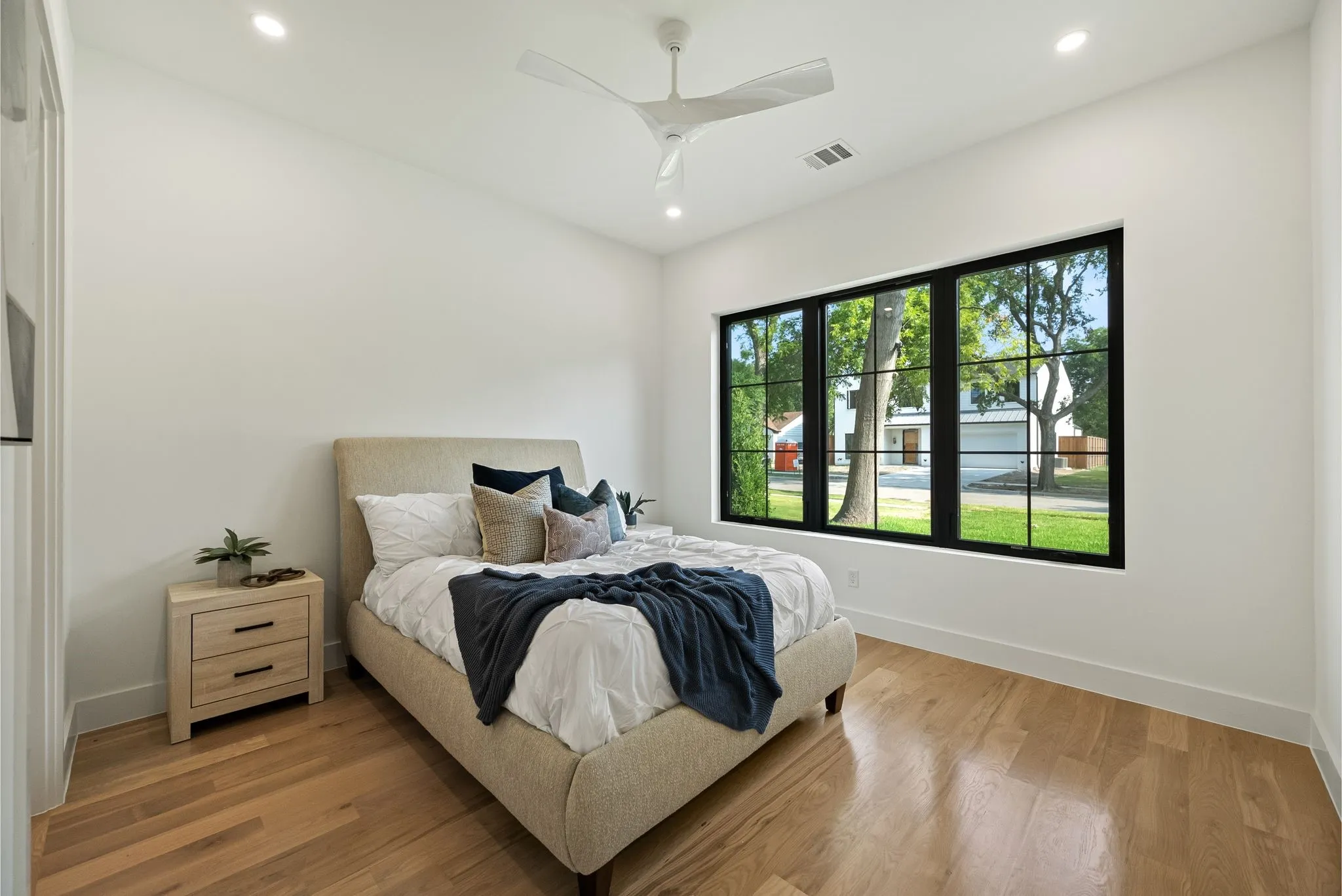 Bedroom featuring wood-finish flooring, a contemporary ceiling fan, recessed lighting, and a large window with black gridded frames