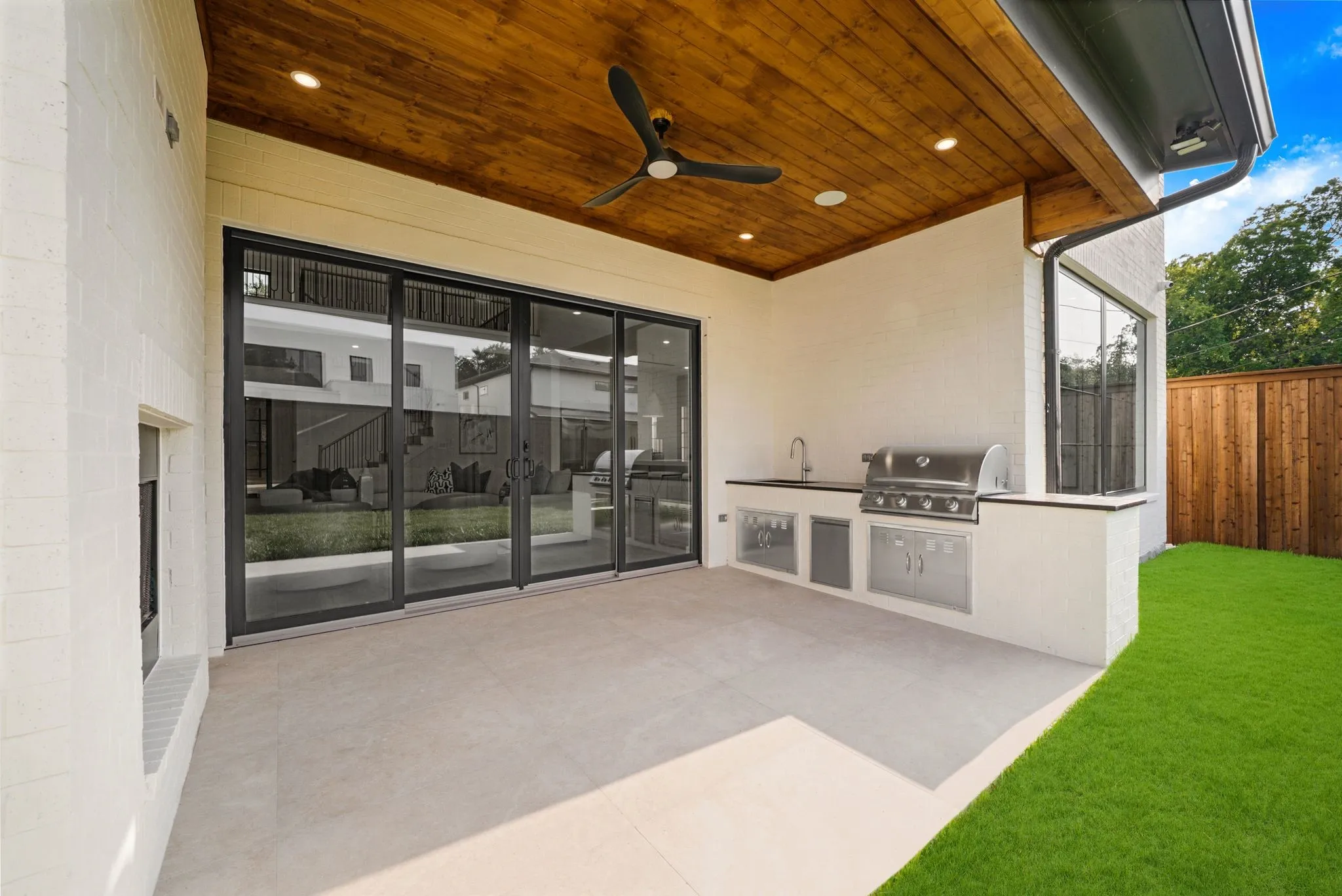 Covered outdoor living space featuring an integrated outdoor kitchen with a built-in grill, sink, and under-counter refrigeration