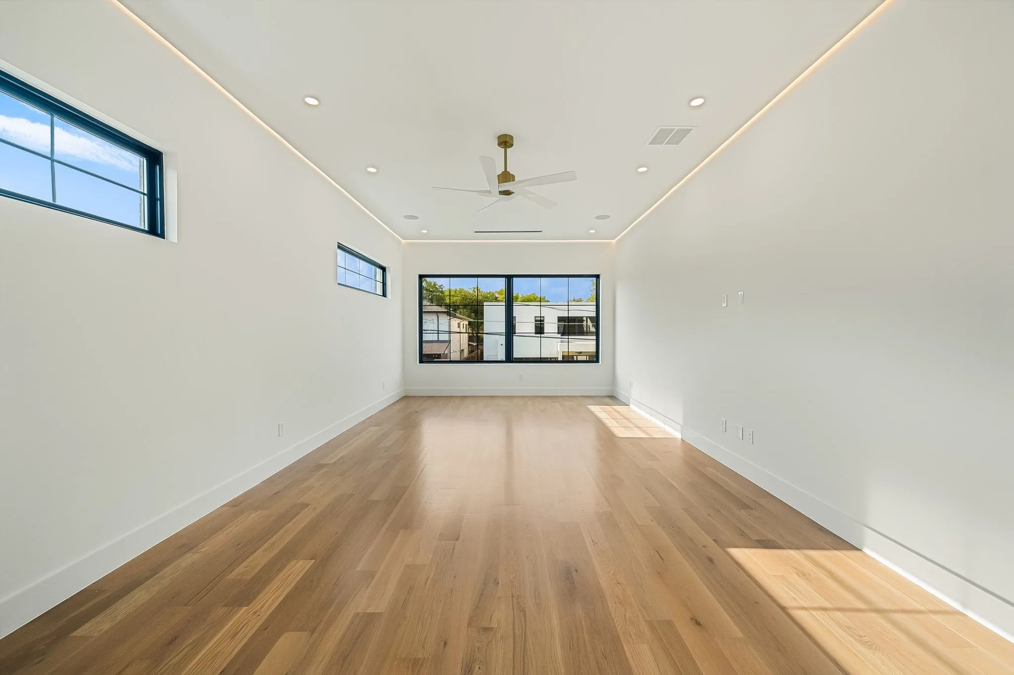 Spacious room featuring wood-finish flooring and multiple windows with dark framing