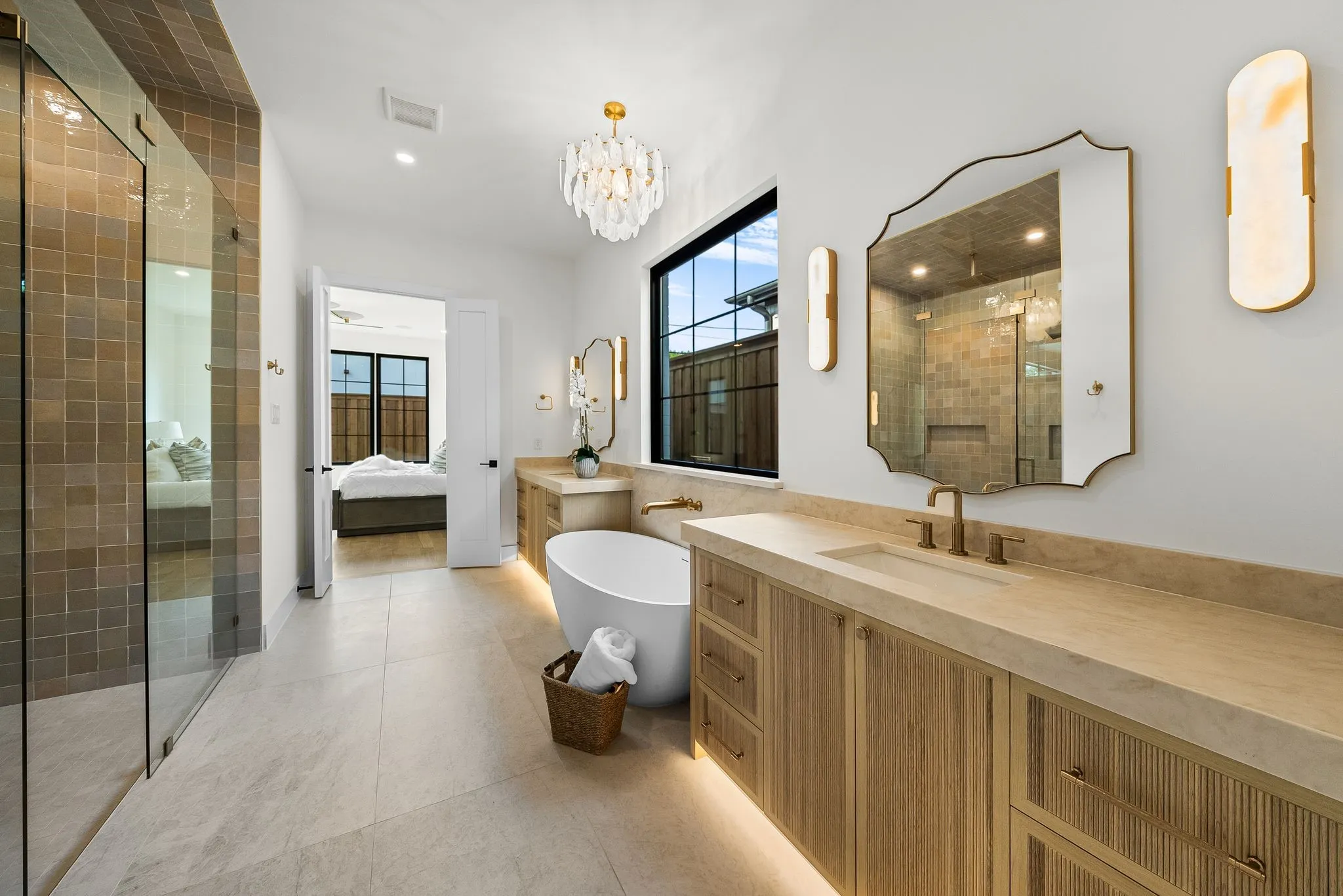 Contemporary bathroom featuring a freestanding tub, dual vanities with integrated sinks, a walk-in shower with glass enclosure, and large format floor tiling