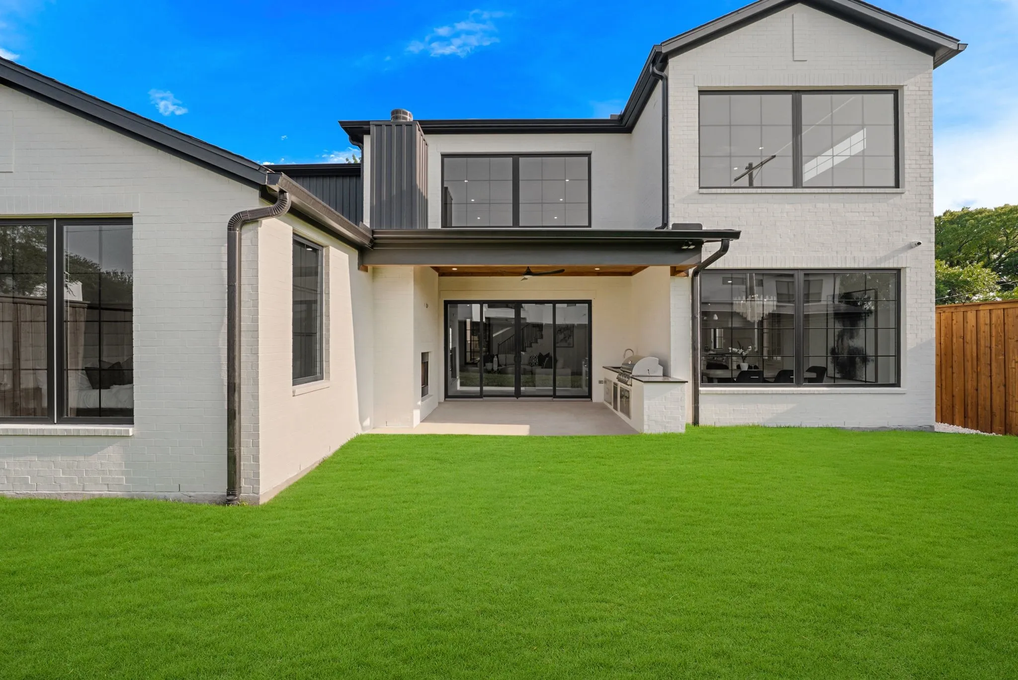 Modern two-story residence featuring a spacious rear facade with extensive glazing, including a large multi-pane window wall and upper-level gable window