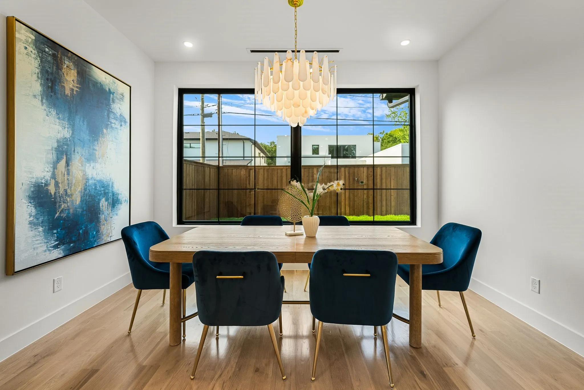 Dining area featuring wood-finish flooring, a contemporary chandelier, and a large black-framed window