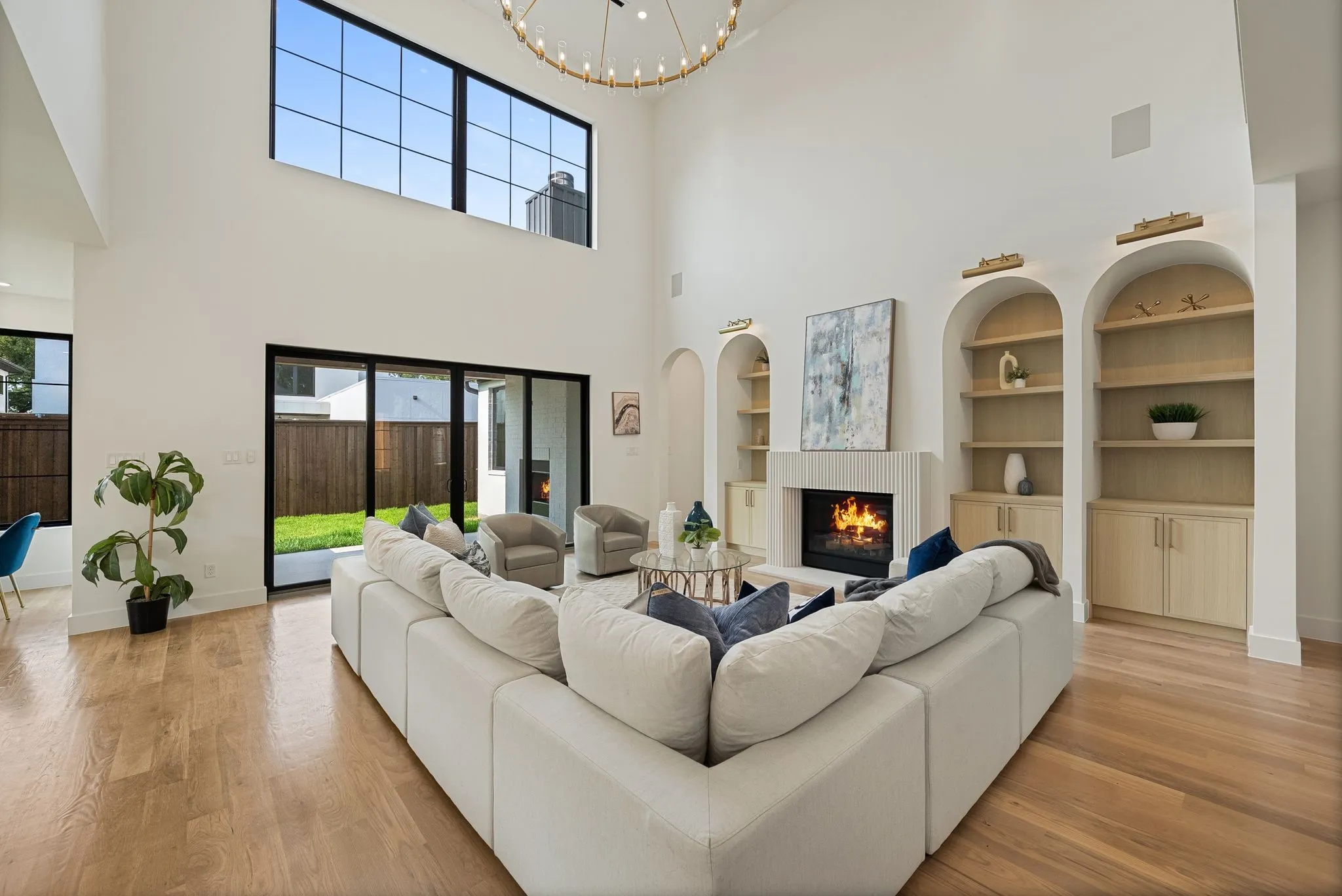 Spacious living area featuring a vaulted ceiling, a fireplace with a fluted surround, and custom arched built-in shelving