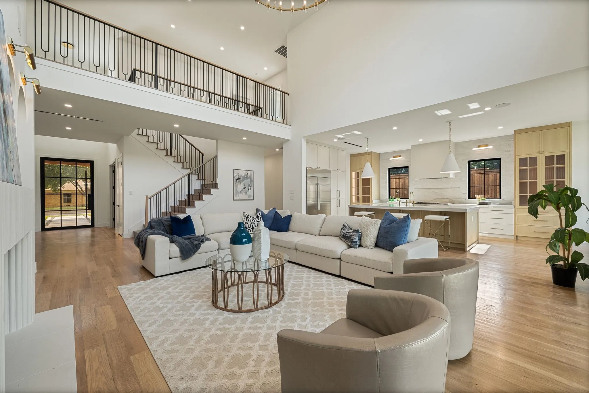 Open-concept living space featuring high ceilings, wood-finish flooring, and a contemporary kitchen with an island