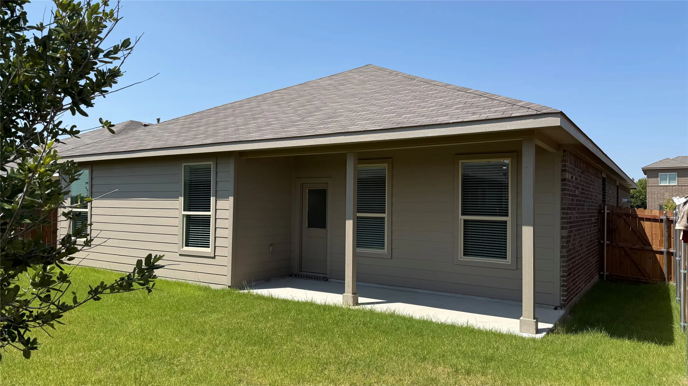 Rear exterior featuring a covered patio, composite shingle roof, horizontal siding, and brick facade