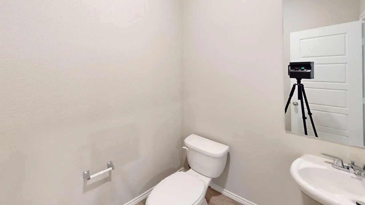 Modern bathroom featuring a white pedestal sink, chrome faucet, and a wall-mounted mirror