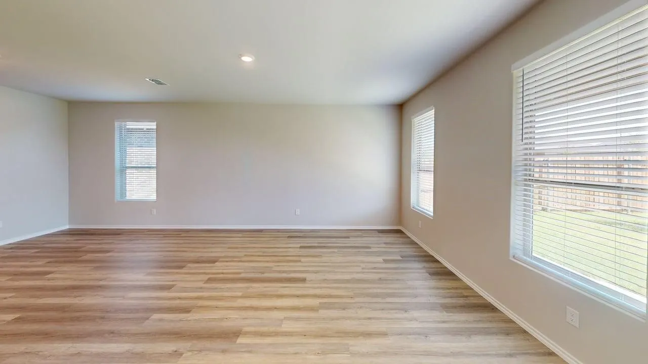 Spacious room featuring wood-finish flooring, neutral wall tones, recessed lighting, multiple windows with blinds, and white baseboards