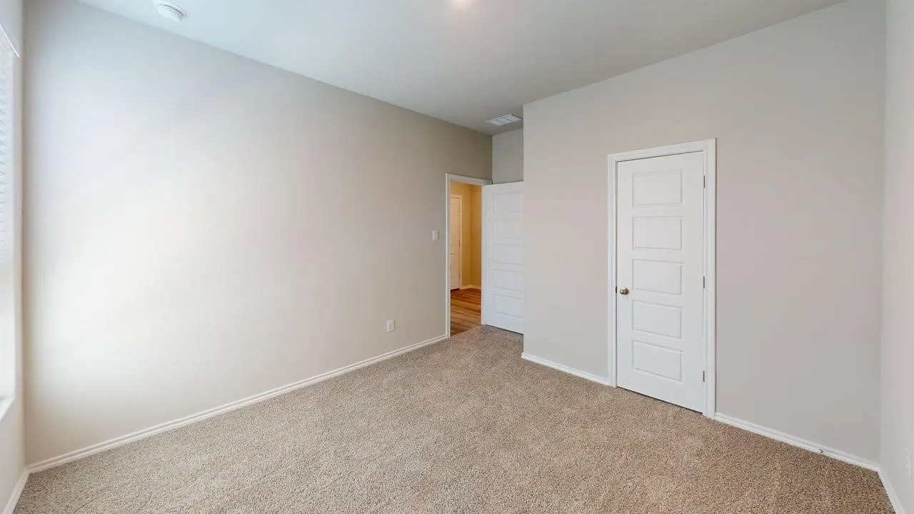 Carpeted room featuring neutral wall tones, white trim, and a contemporary five-panel interior door