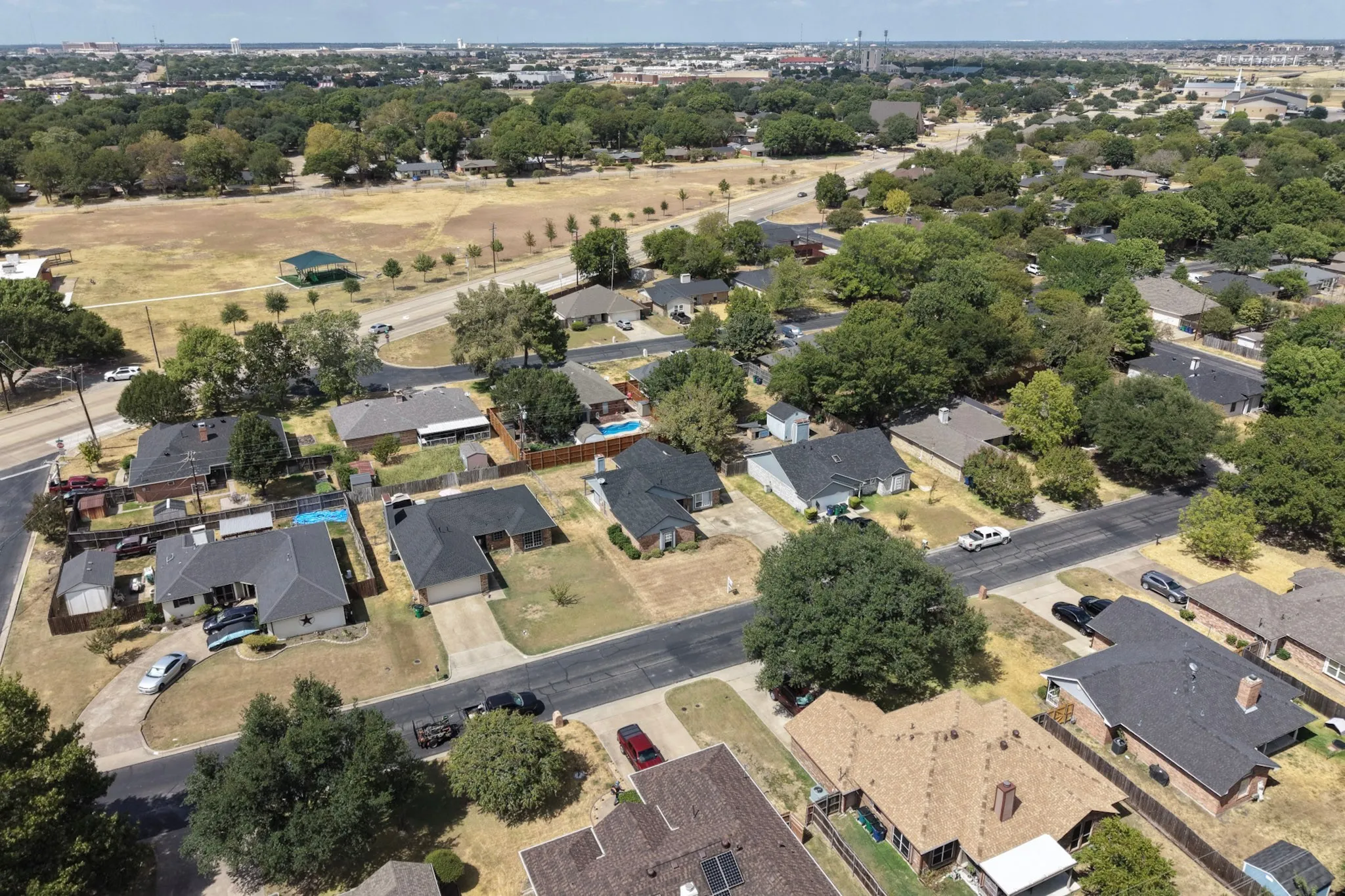 Residential neighborhood with mature trees, paved streets, and a variety of single-story homes