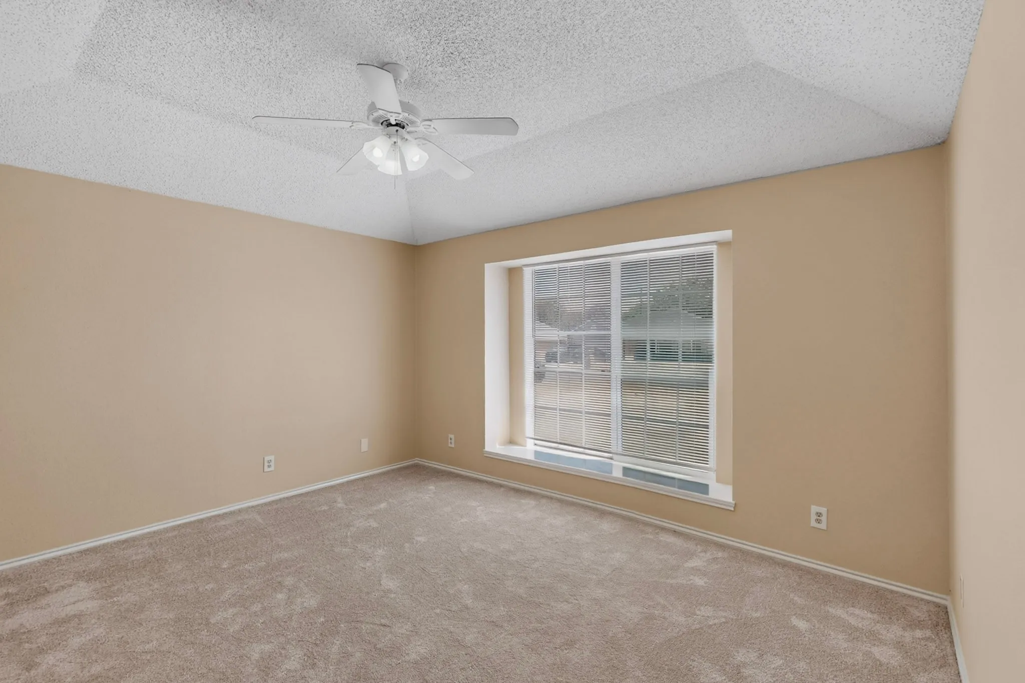 Neutral-toned wall paint, carpet flooring, a window with horizontal blinds, and a ceiling fan with integrated lighting