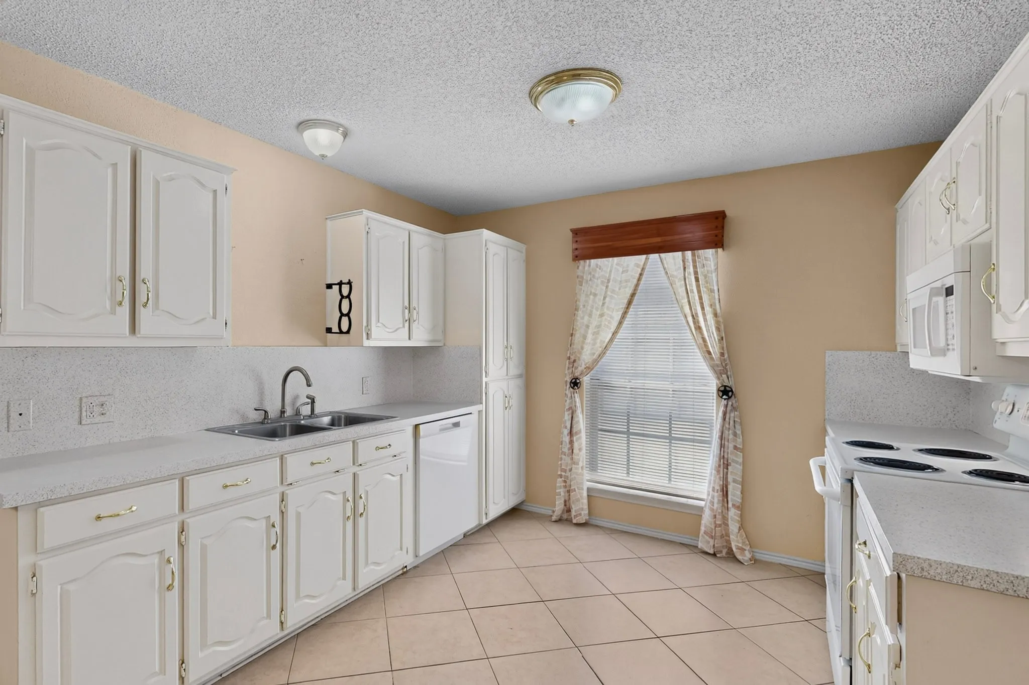 Full kitchen with white cabinetry, light-toned countertops, and a dual basin sink