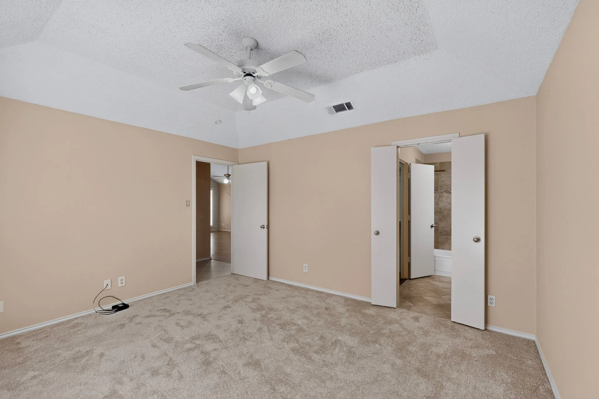 Vaulted ceiling, ceiling fan, neutral carpet, bi-fold closet doors, and a full bathroom with a tub