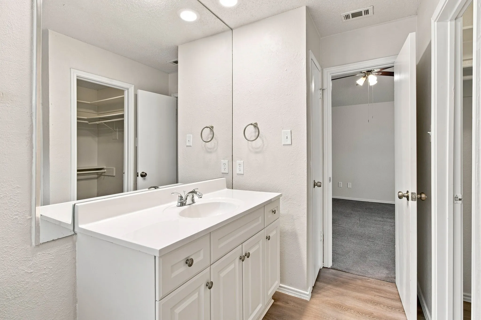 Bathroom vanity with integrated sink, chrome faucet, and expansive mirror