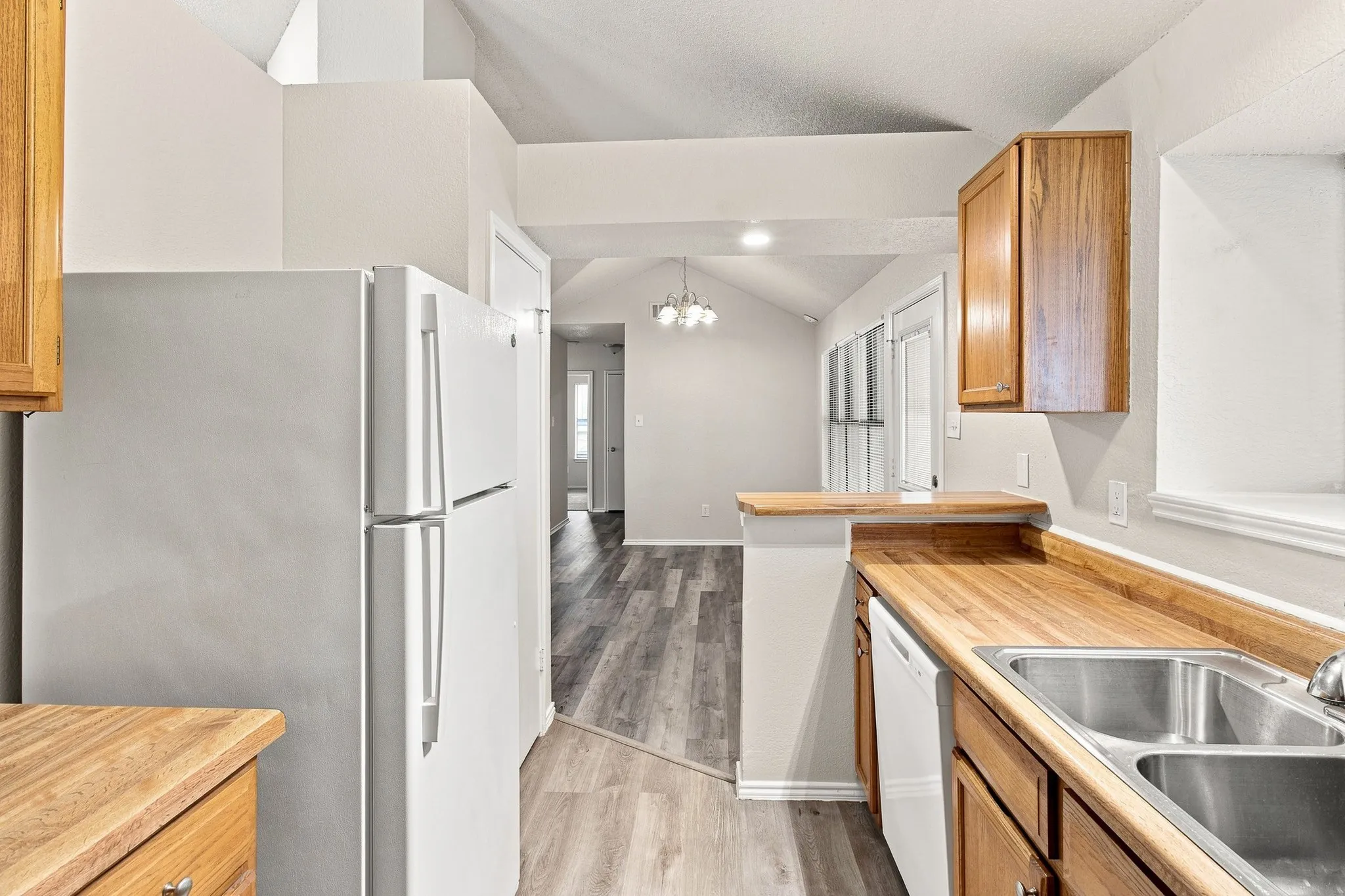 Kitchen featuring warm wood-finish countertops, wood cabinetry, and a double basin stainless steel sink