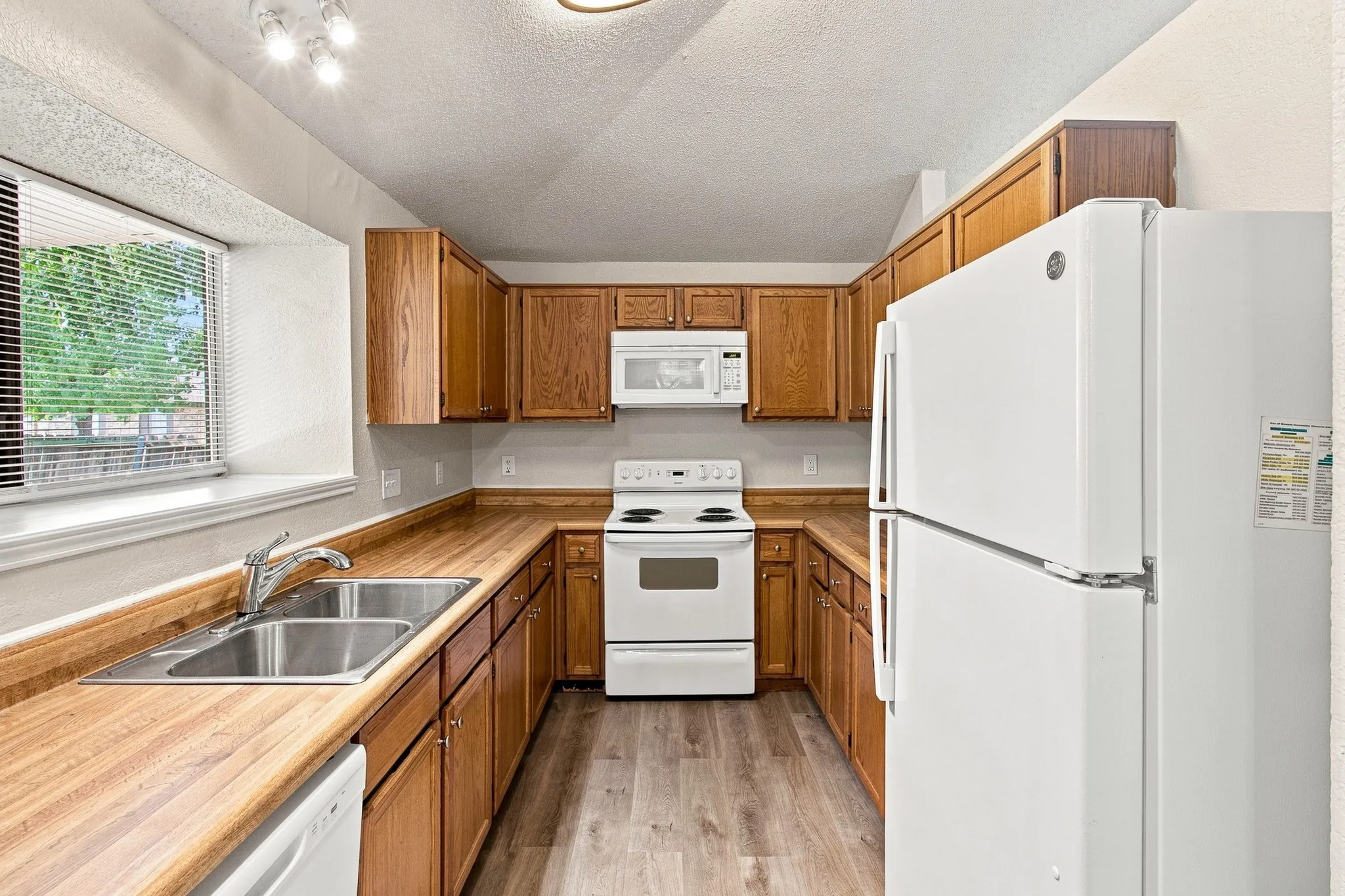U-shaped kitchen featuring wood-finish countertops, wood cabinetry, and a double basin stainless steel sink